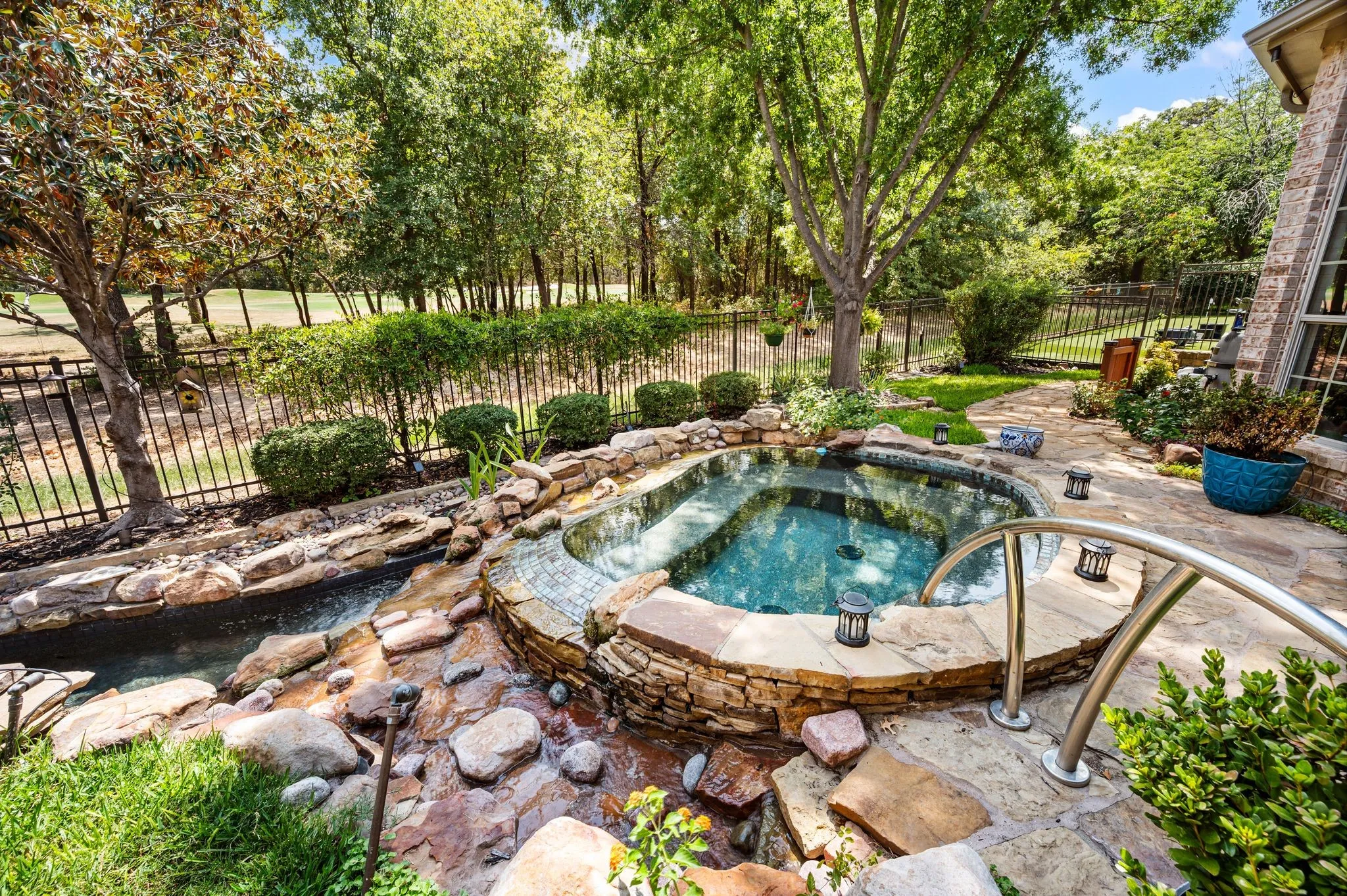 Resort-style backyard features a pool, cascading water elements & beautiful golf course surroundings.