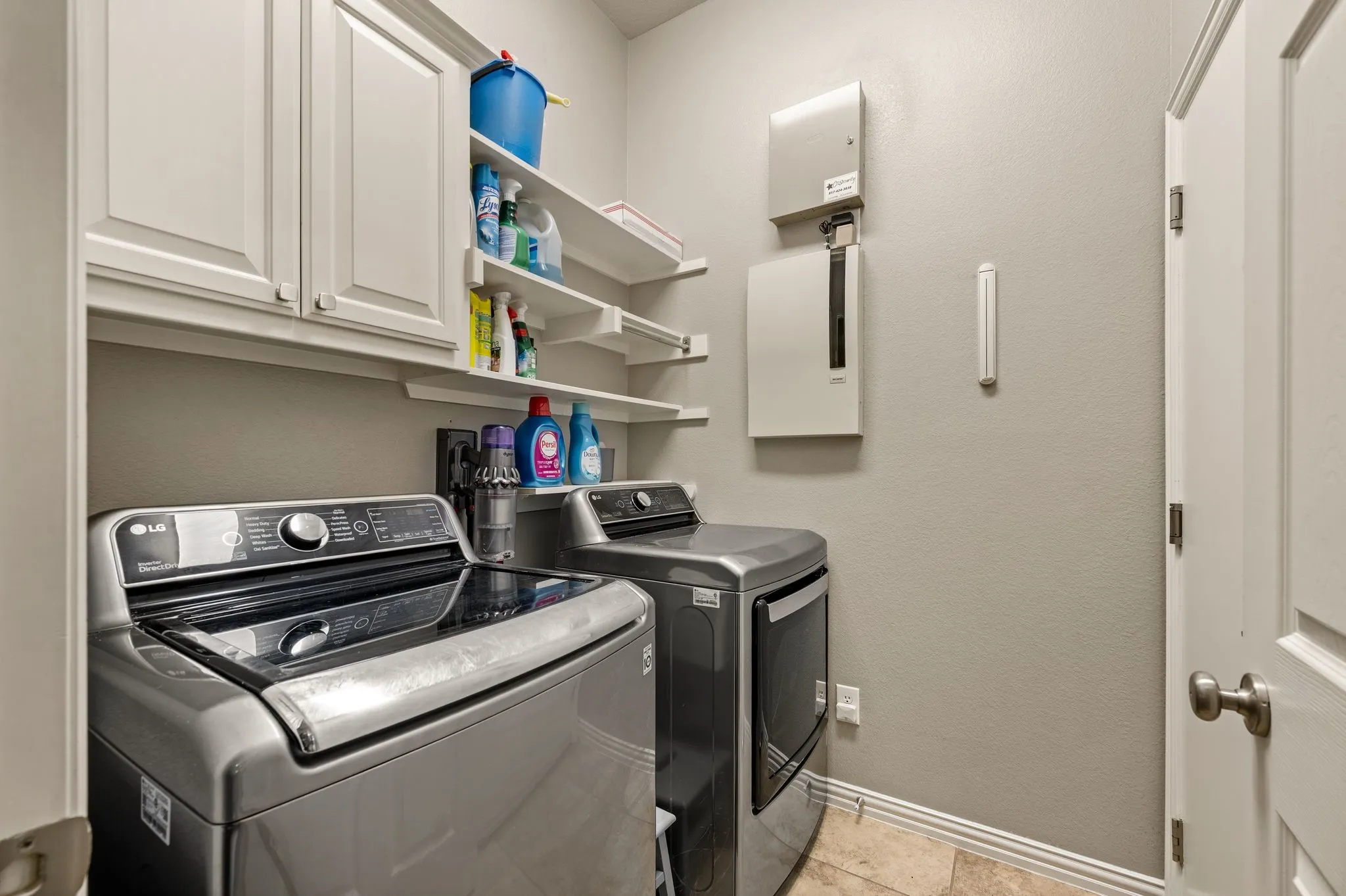 Separate laundry room includes built-in cabinetry & open shelving for convenient household storage.