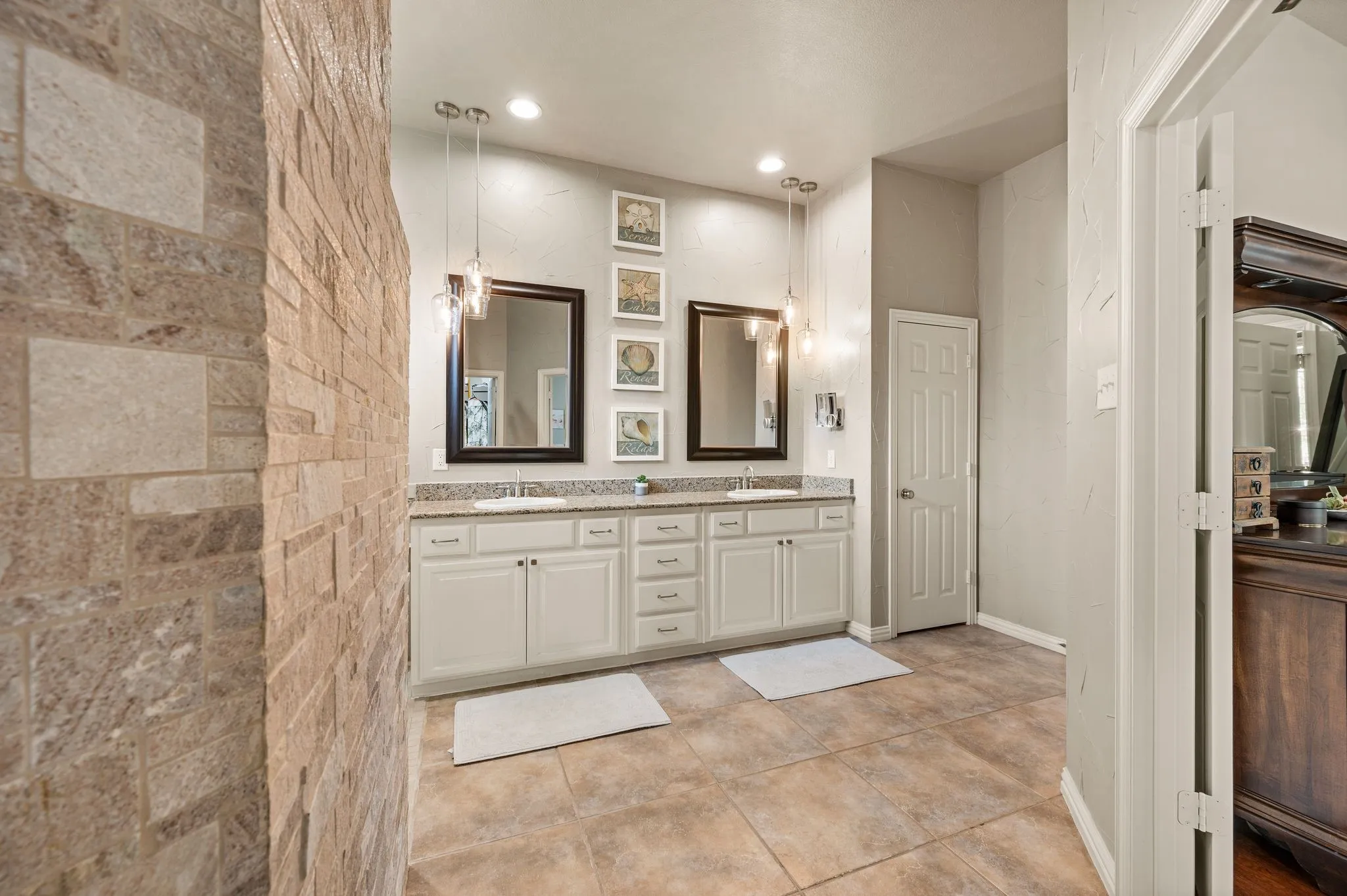 Another view of the primary bath highlights dual vanities, abundant storage & the statement tiled shower.