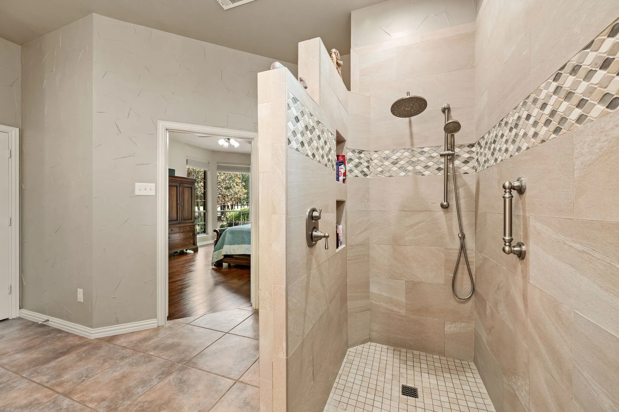 Impressive walk-in shower includes floor-to-ceiling tile, decorative accents, a rain showerhead & handheld sprayer and dual recessed shampoo/soap boxes.