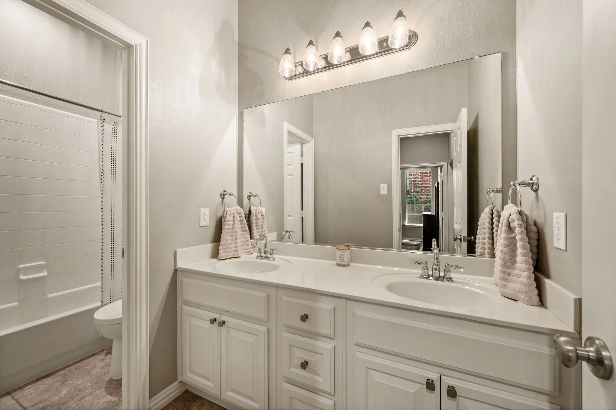 Secondary bathroom offers a dual-sink vanity with plenty of cabinet storage & a separate tub and shower area.