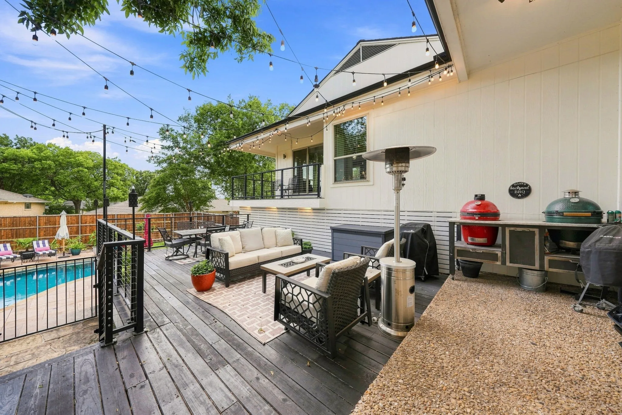Expansive outdoor deck with a private pool, an upper-level balcony, a built-in outdoor kitchen station, and a gravel-finish patio area