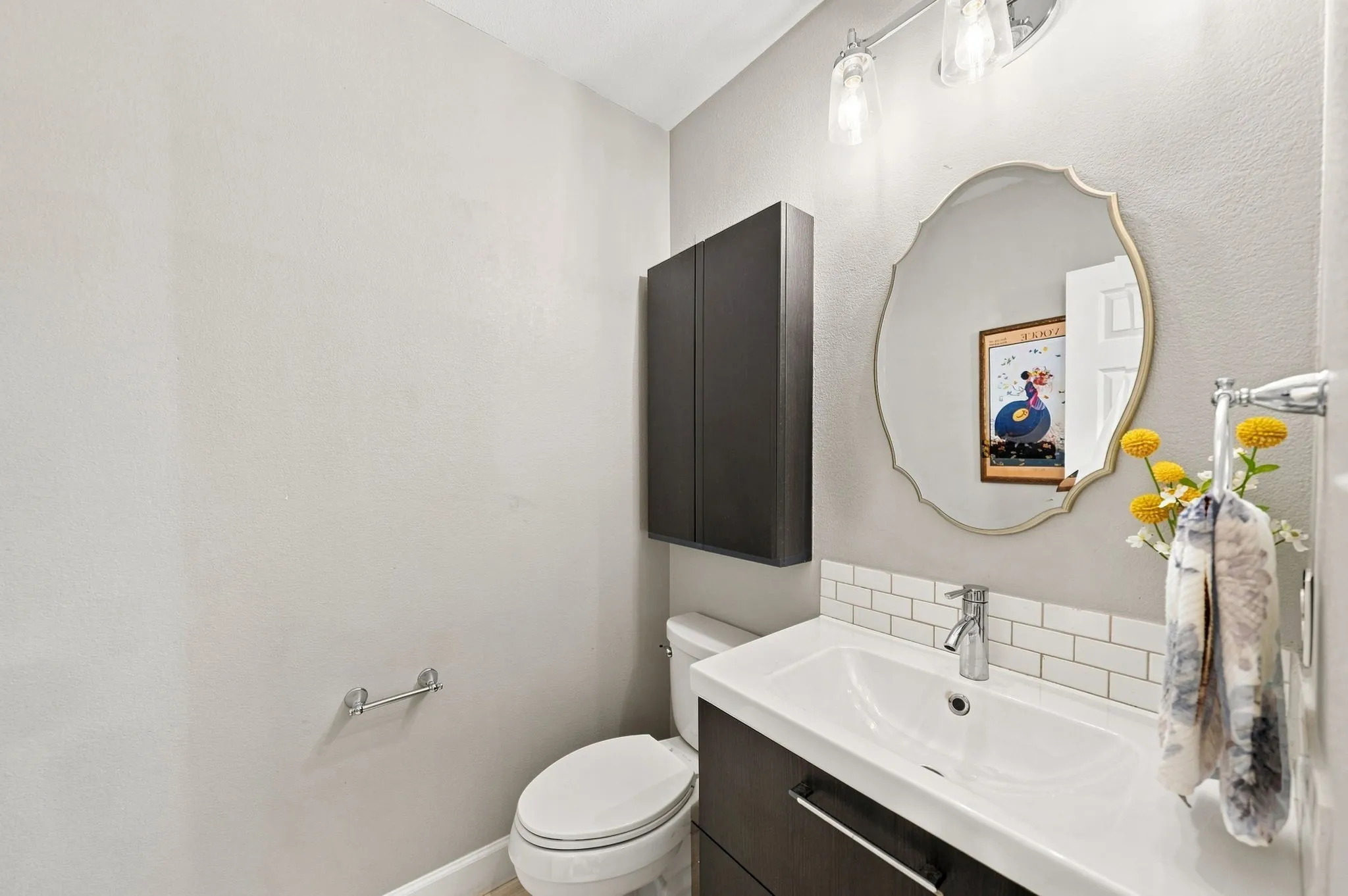 Contemporary vanity with integrated sink, subway tile backsplash, wall-mounted storage cabinet, and decorative mirror