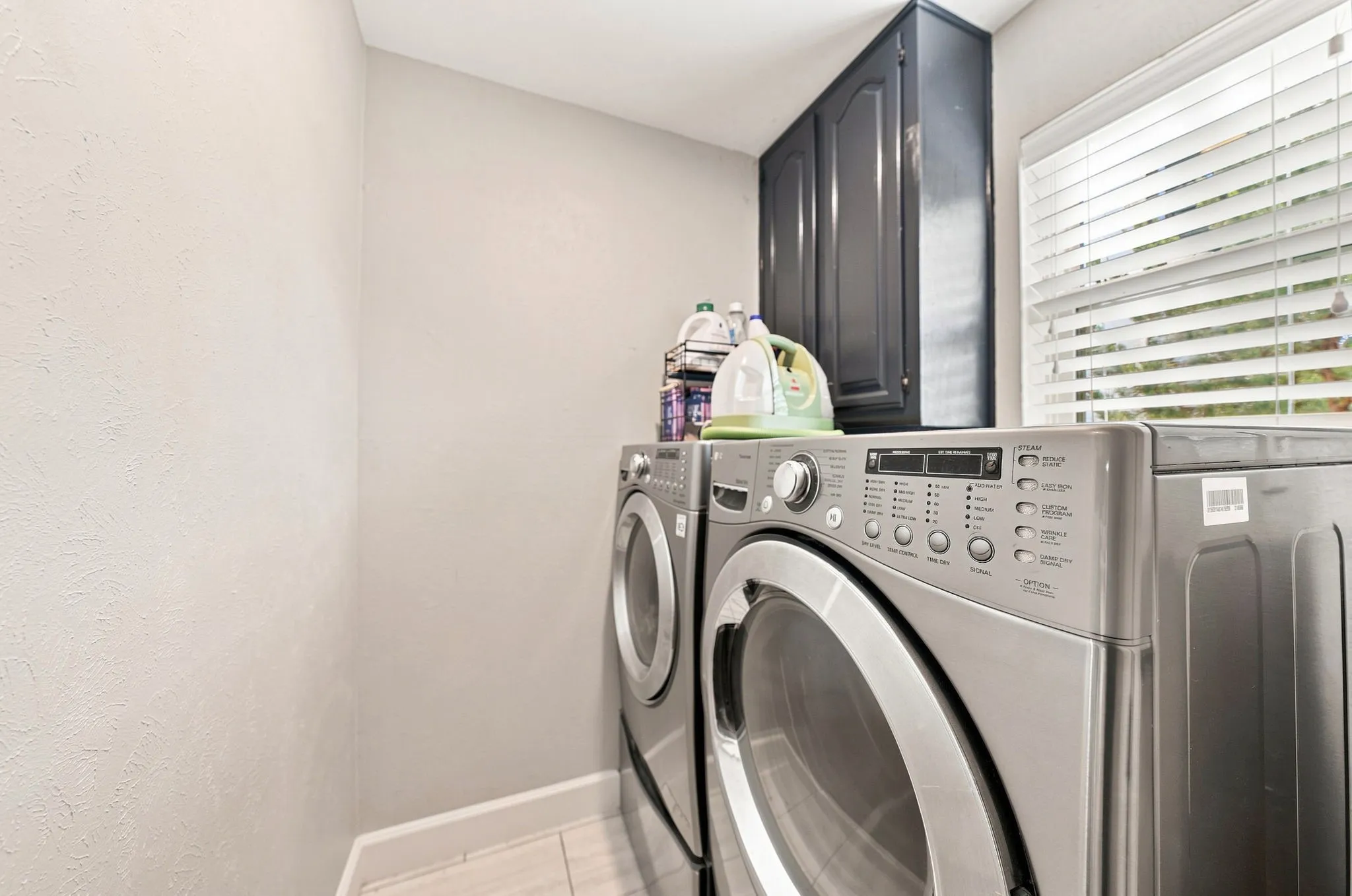 Built-in cabinetry, window with blinds, and tile flooring