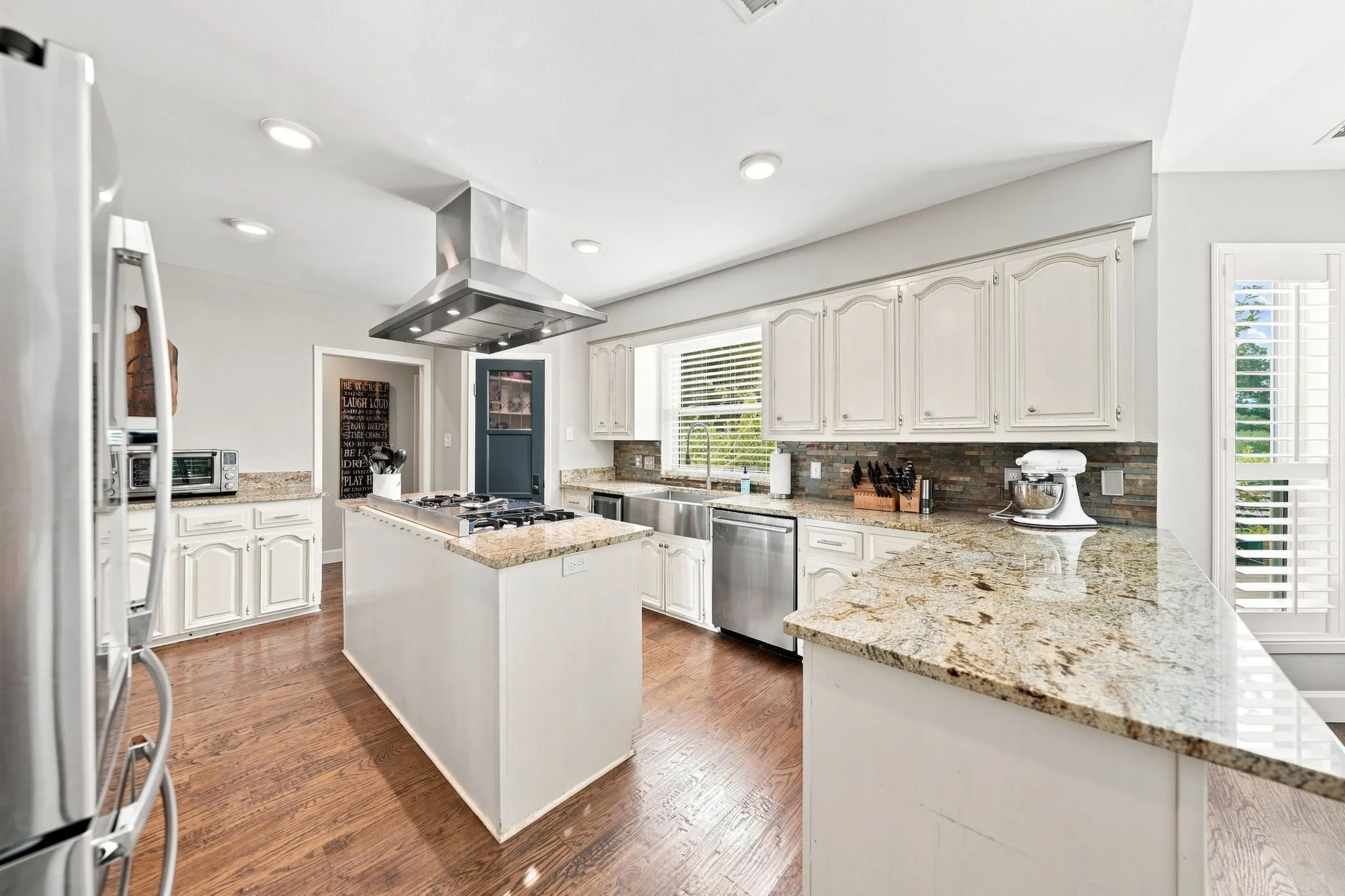 Kitchen featuring wood-finish flooring, white cabinetry, granite countertops, and stainless steel appliances