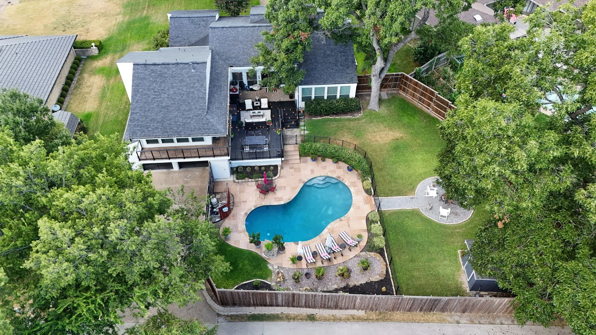 Exterior featuring a multi-level deck, fenced backyard, and a freeform swimming pool with integrated spa