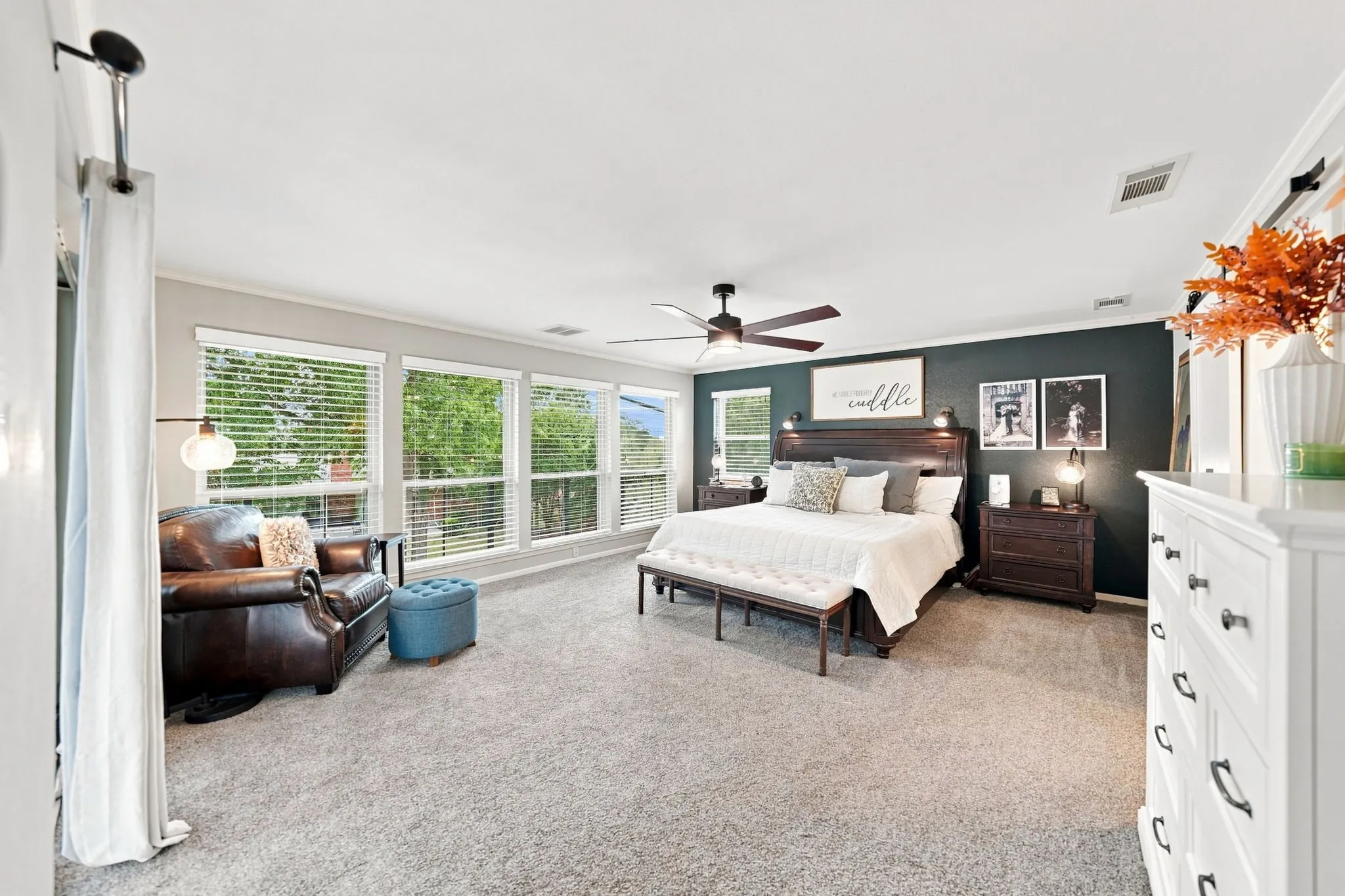 Expansive room with neutral carpet, multiple large windows, and a ceiling fan