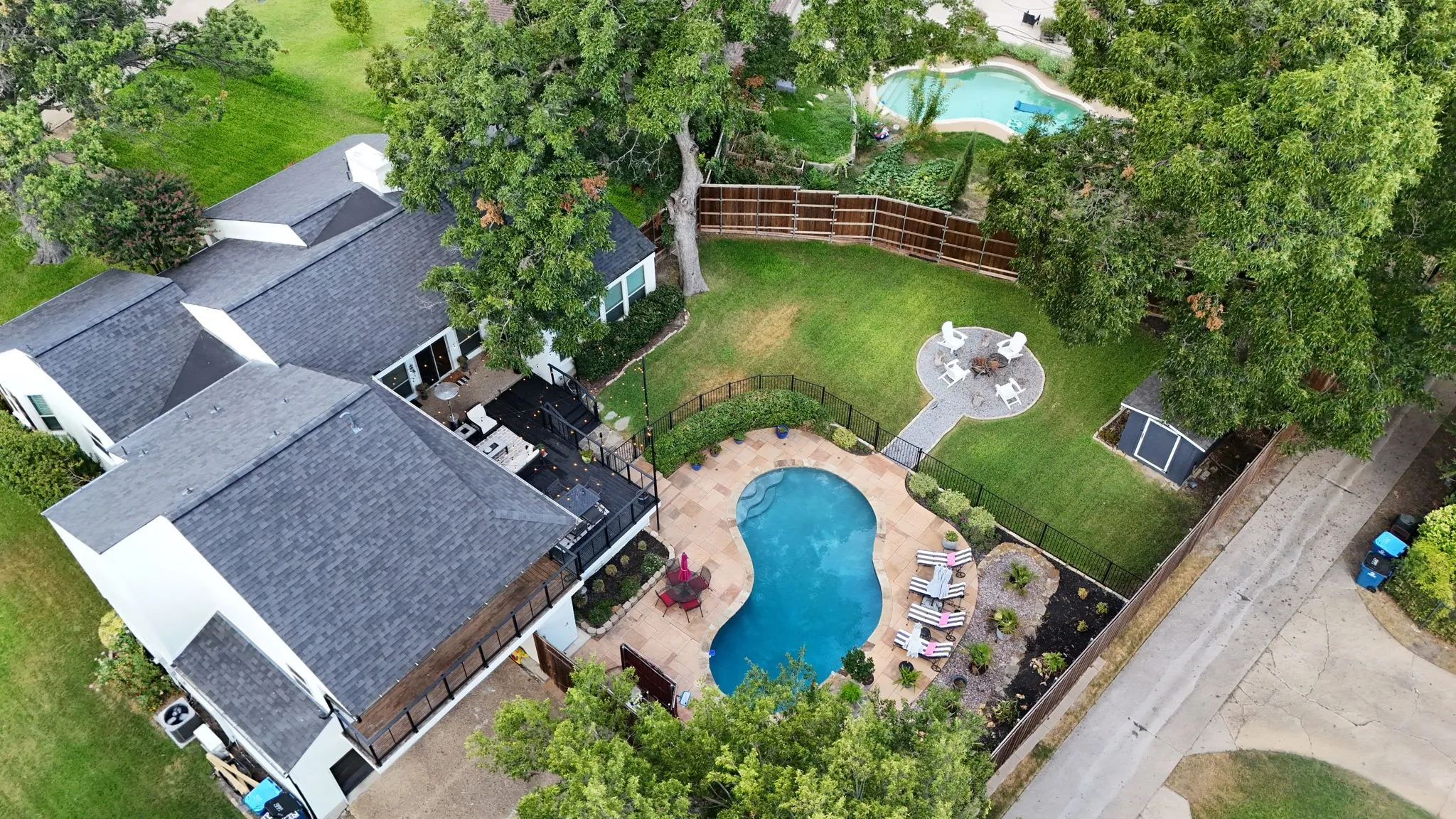 Expansive backyard with a curved swimming pool, dedicated lounging area, and a fire pit with seating