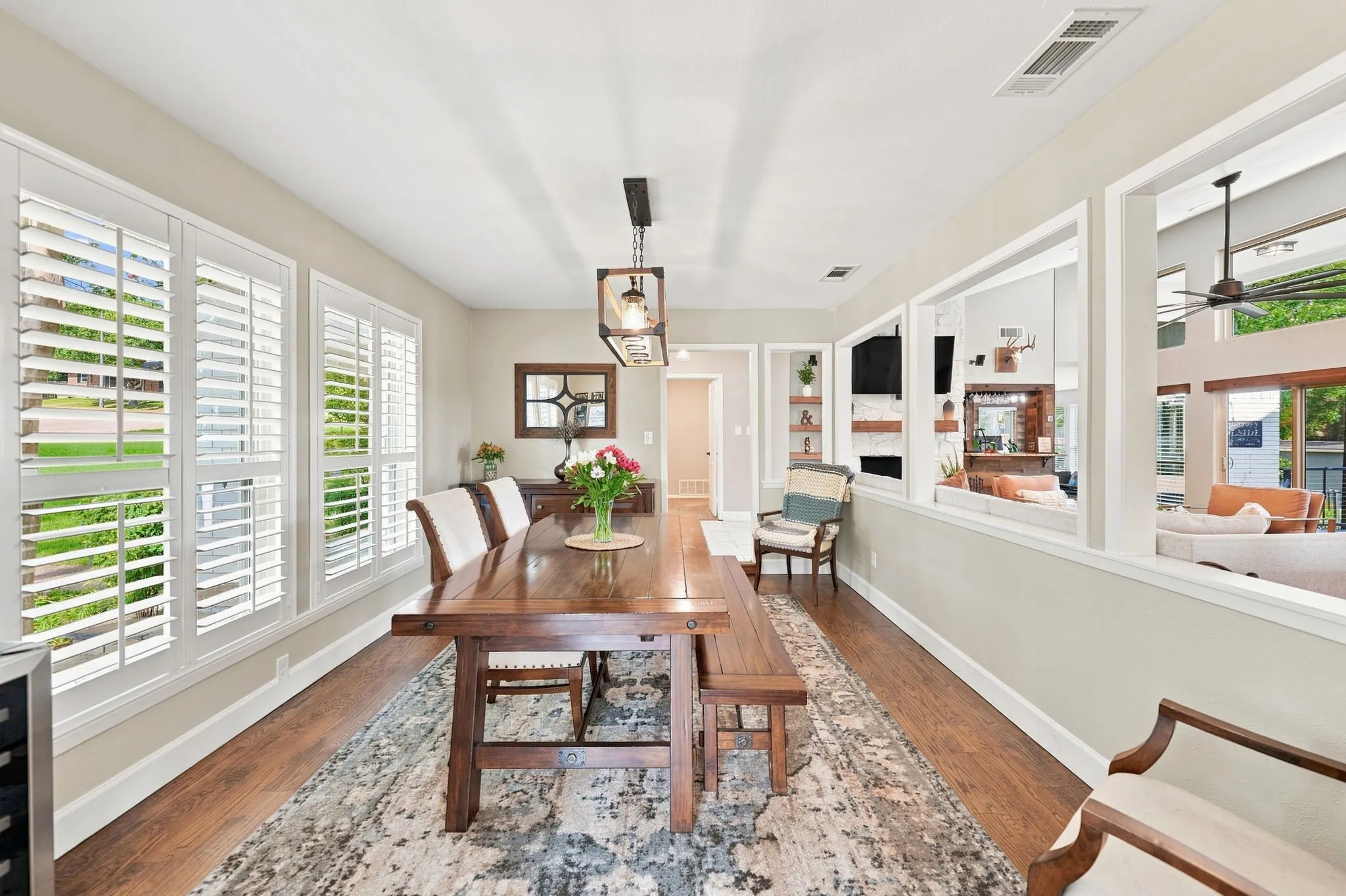 Wood-finish flooring throughout, multiple windows with white plantation shutters, built-in shelving, and a decorative light fixture