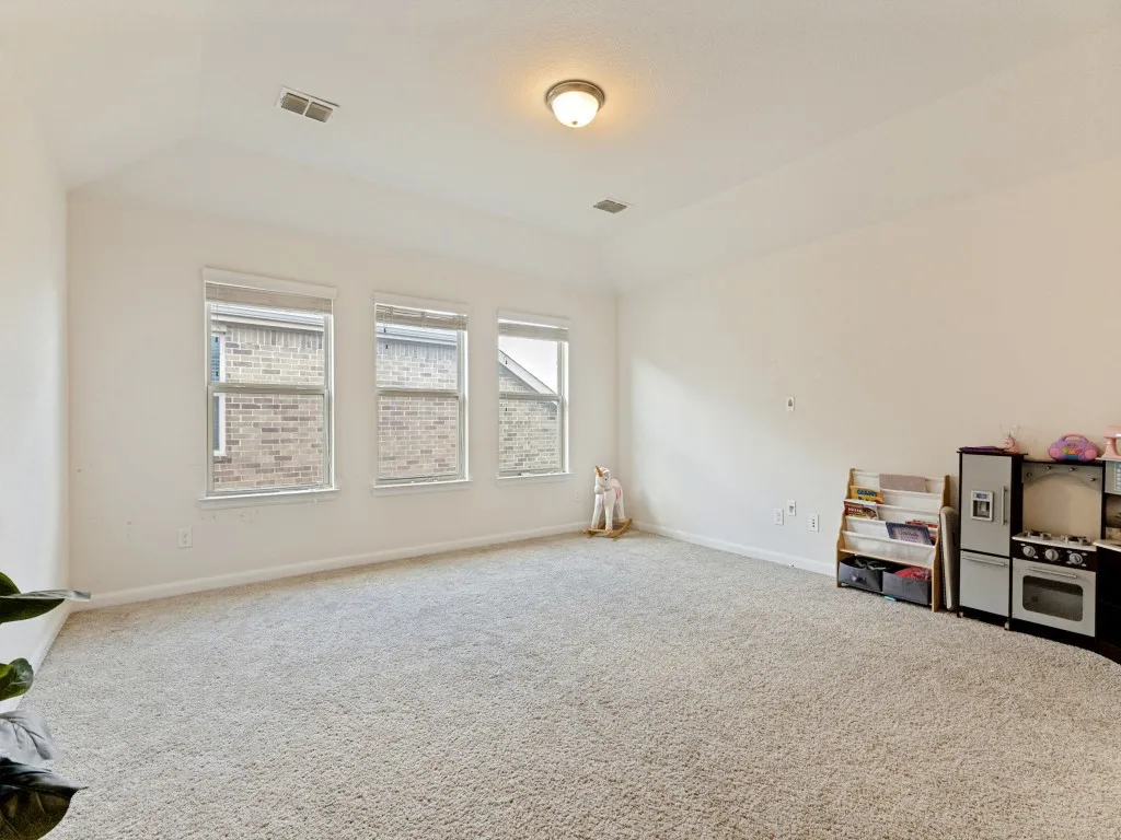 Carpeted room featuring three windows with blinds, a vaulted ceiling, and recessed lighting