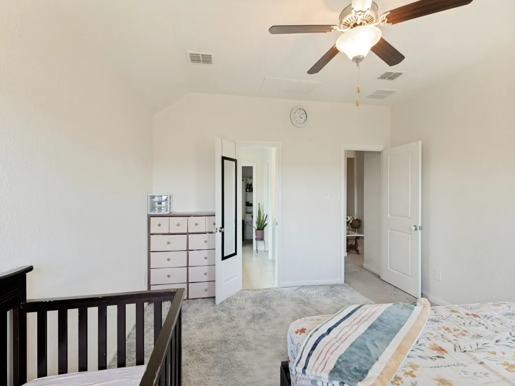 Textured walls, ceiling fan with integrated lighting, paneled interior doors, and carpet flooring