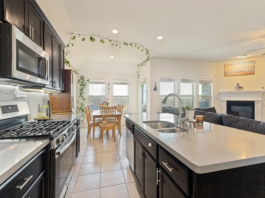 Gourmet kitchen with stainless steel appliances, dark wood cabinetry, white subway tile backsplash, and light-toned countertops