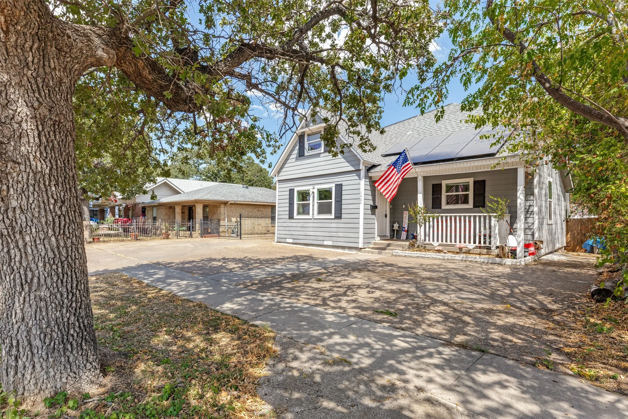 Gray siding exterior with a covered front porch, white railing, and black window shutters
