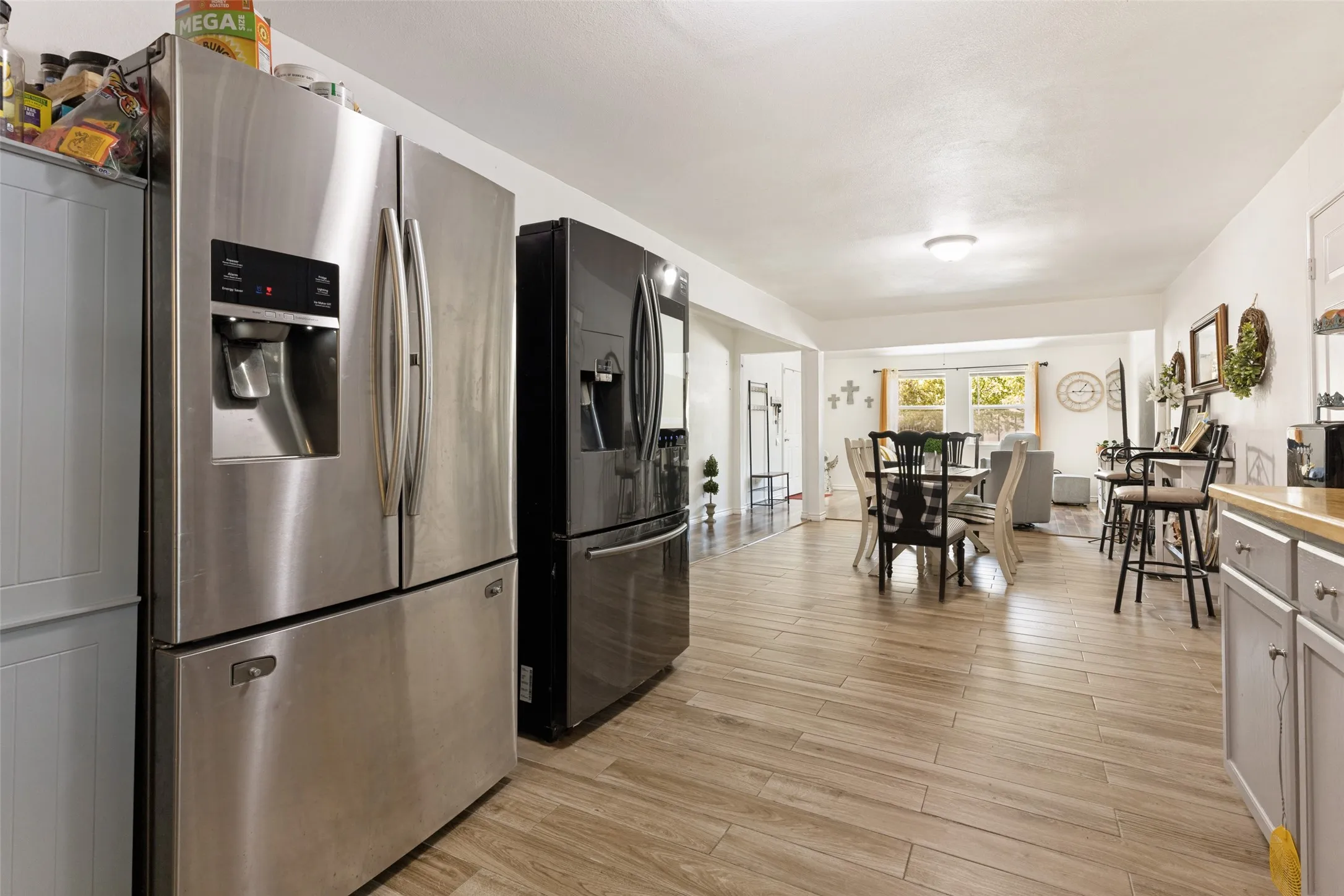 Stainless steel French door refrigerator, wood-finish flooring, white walls, and built-in cabinetry with wood-finish countertops