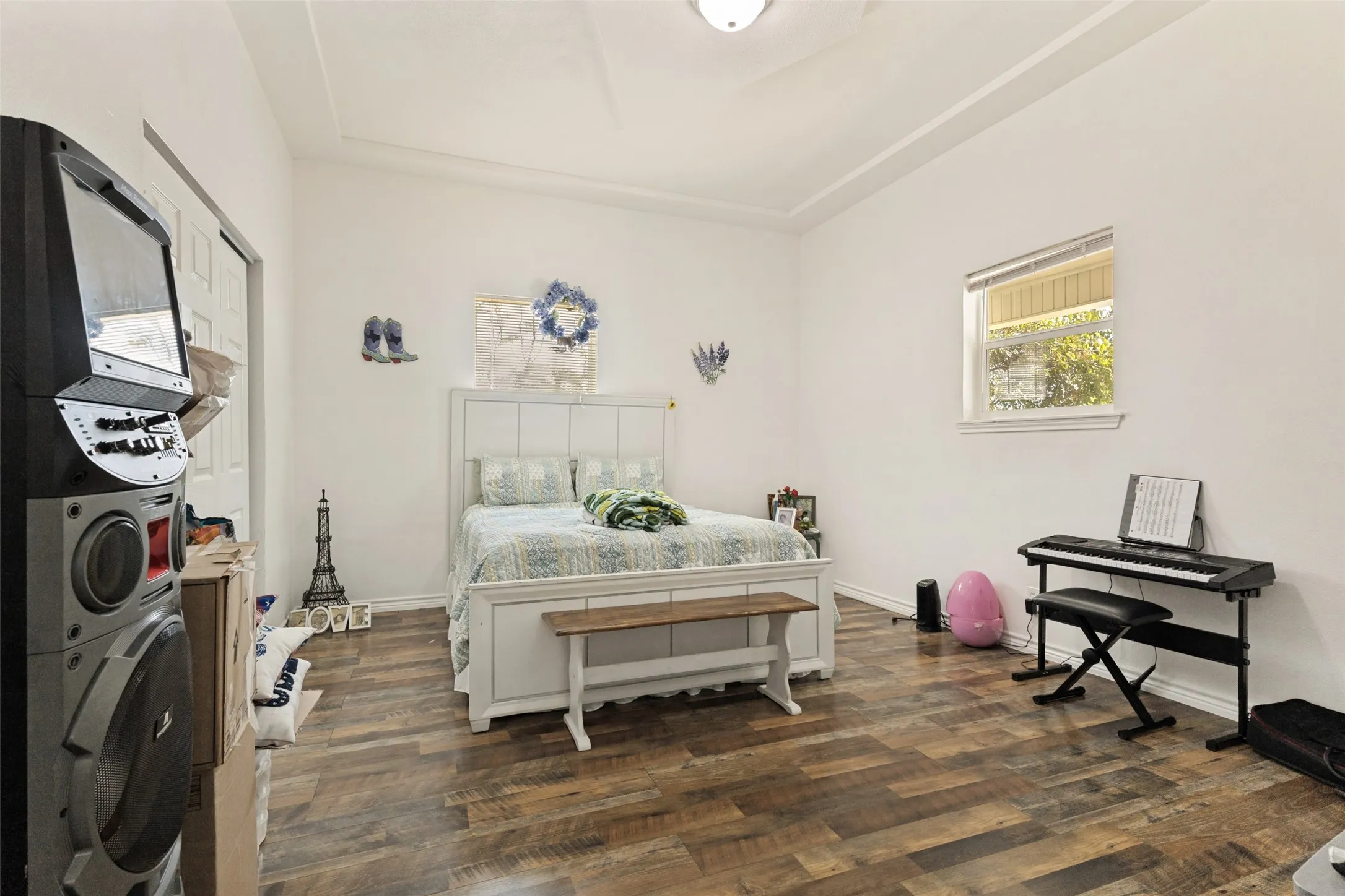 Wood-finish flooring, white walls, tray ceiling, recessed lighting, and a single window with blinds