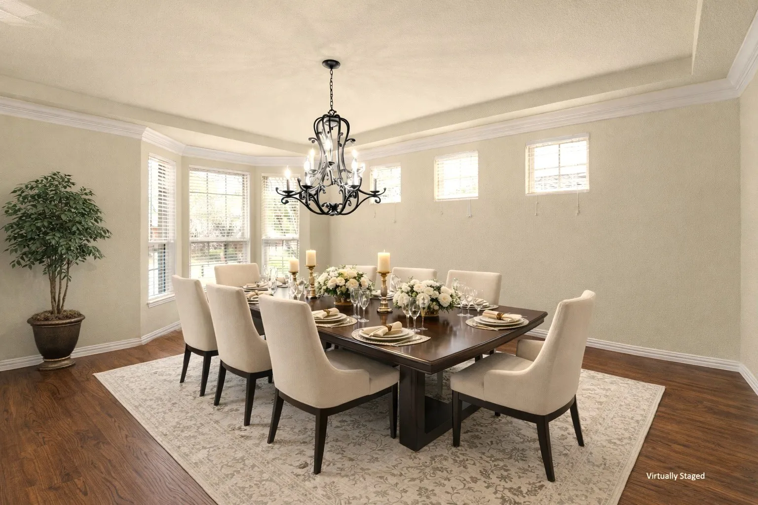 Recessed tray ceiling with crown molding, wood-finish flooring, bay window with blinds, and an overhead chandelier