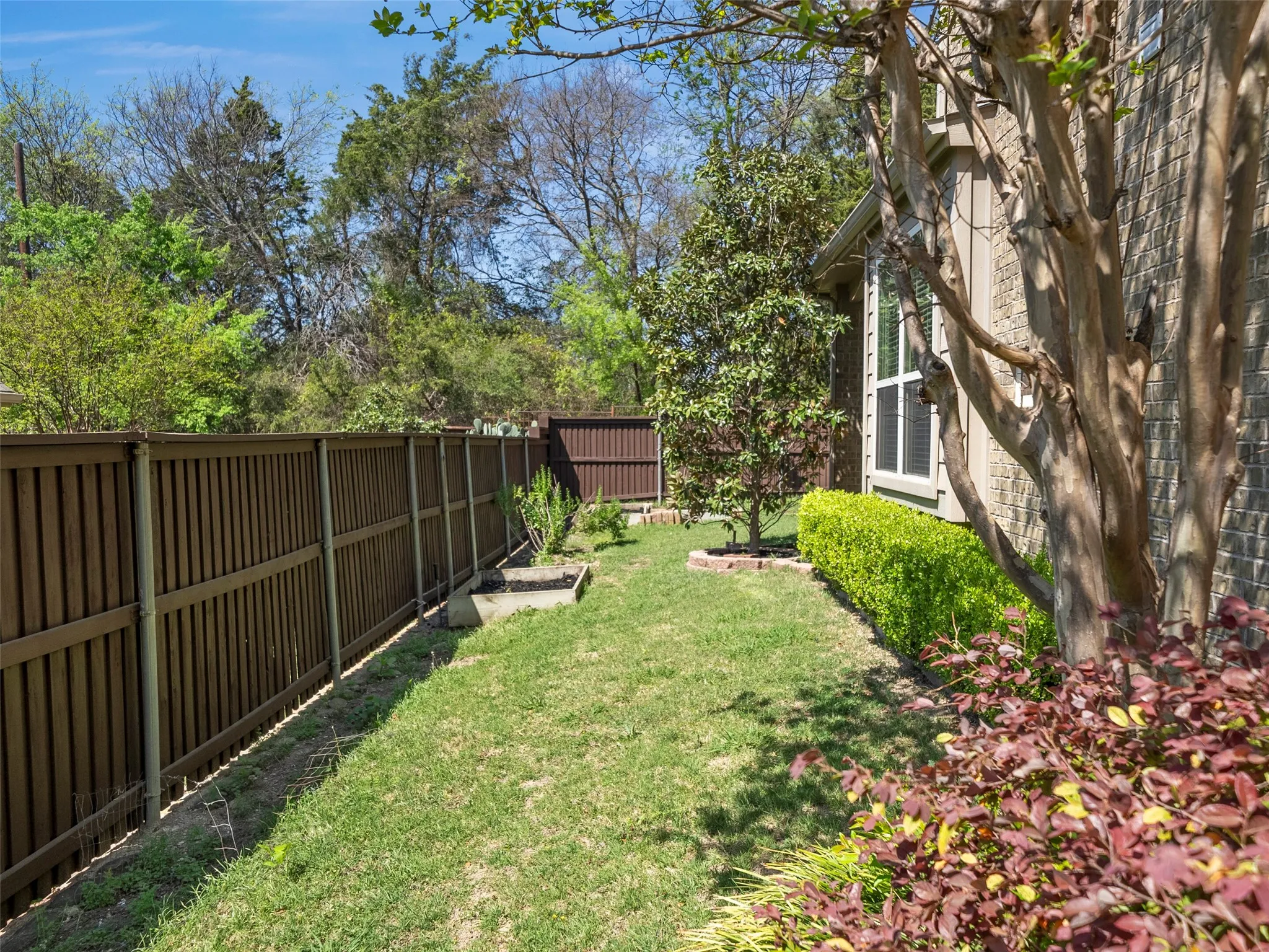 Expansive backyard featuring a manicured lawn, wood fencing, and mature trees