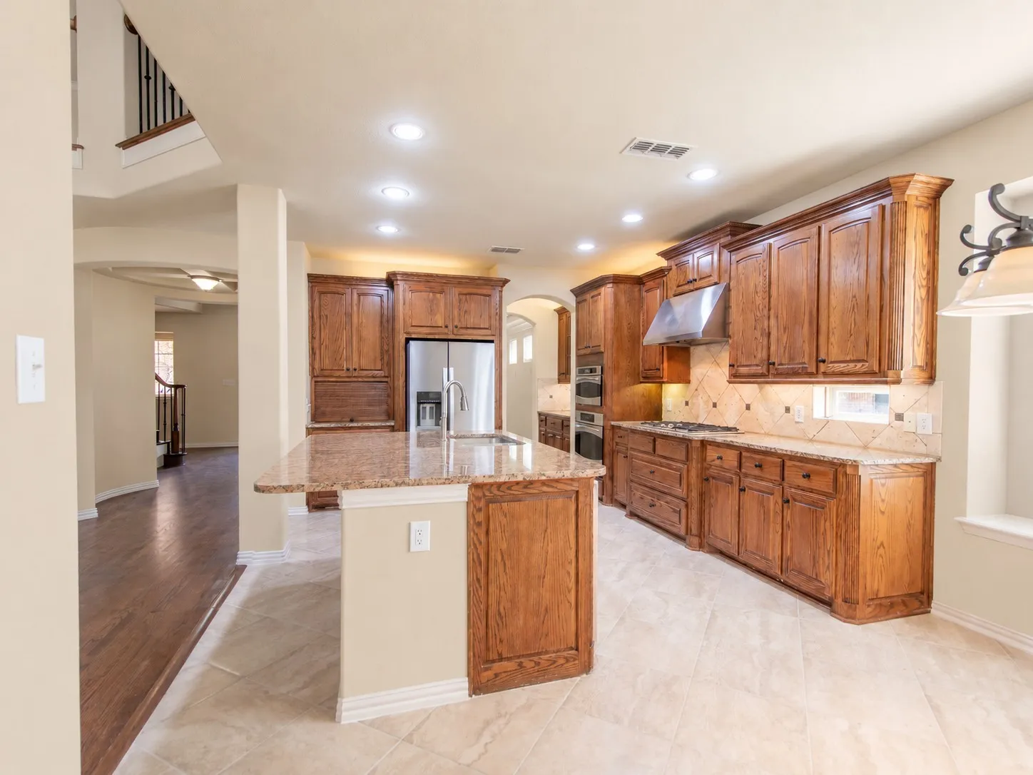 Spacious kitchen featuring extensive wood cabinetry, granite countertops, tile flooring, stainless steel appliances, and recessed lighting