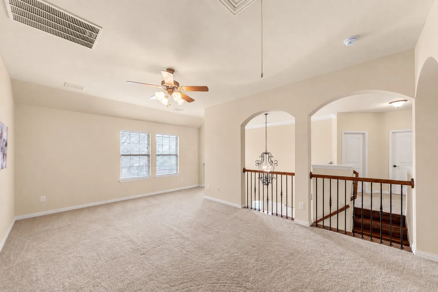 Carpeted room with multiple windows, a ceiling fan, and architectural arched openings