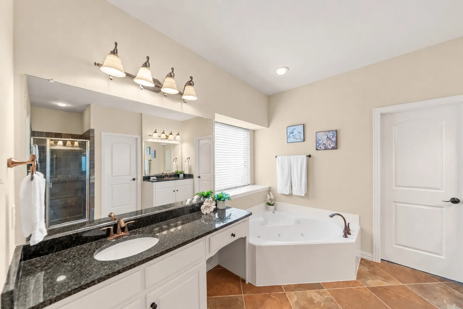 Dual vanity with dark granite-finish countertop, undermount sinks, and bronze-finish fixtures