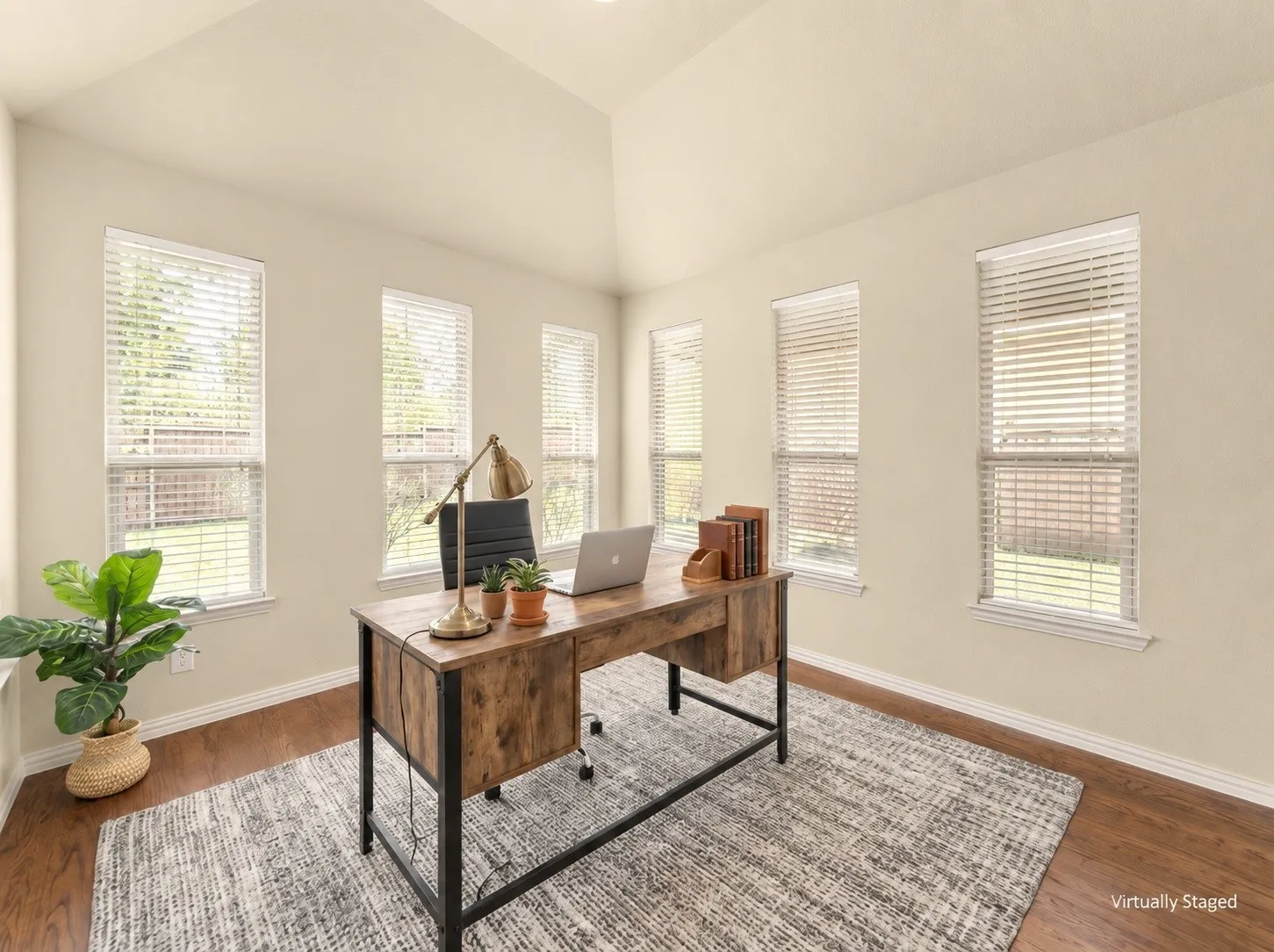 Vaulted ceiling, multiple windows with blinds, light-toned wall paint, and wood-finish flooring