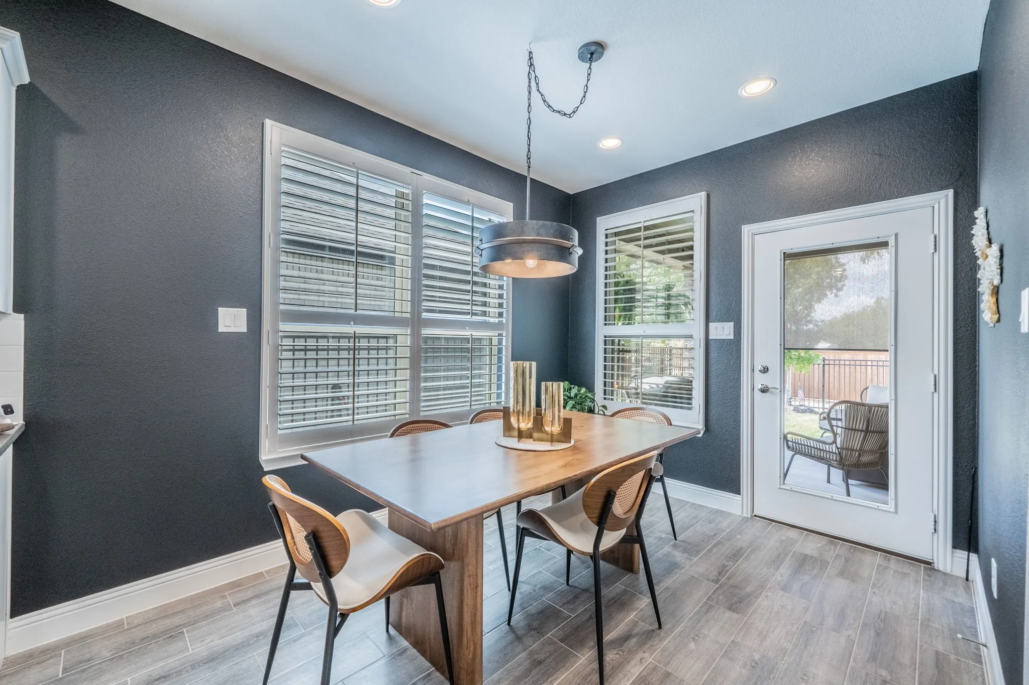 GORGEOUS breakfast room featuring large windows with plantation shutters and decorative lighting. This door takes you to the covered patio.