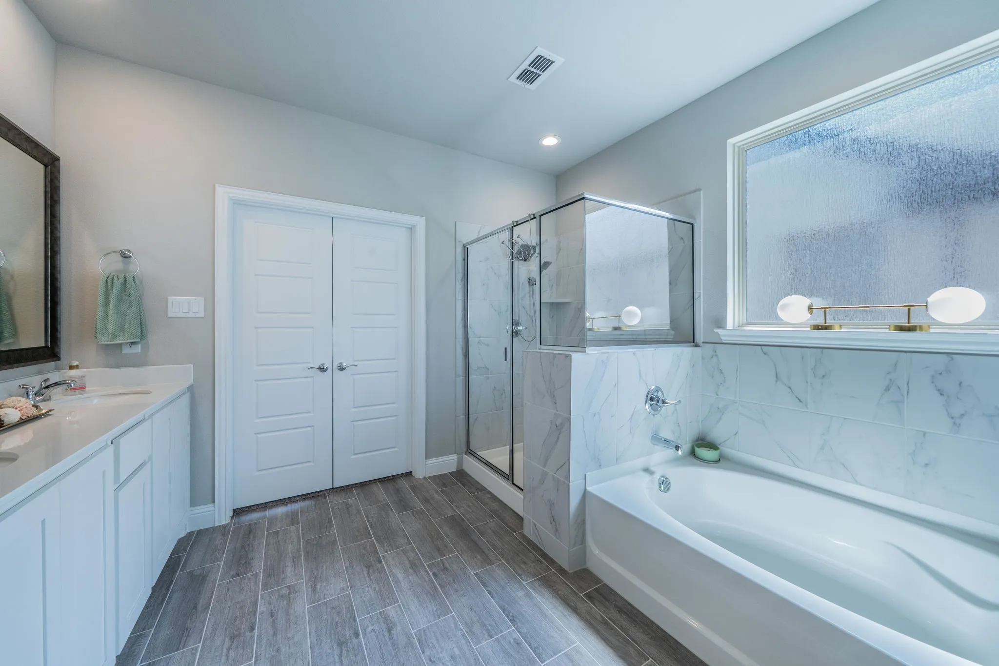Another view of the primary bathroom facing the door; notice the large soaking tub and natural light!