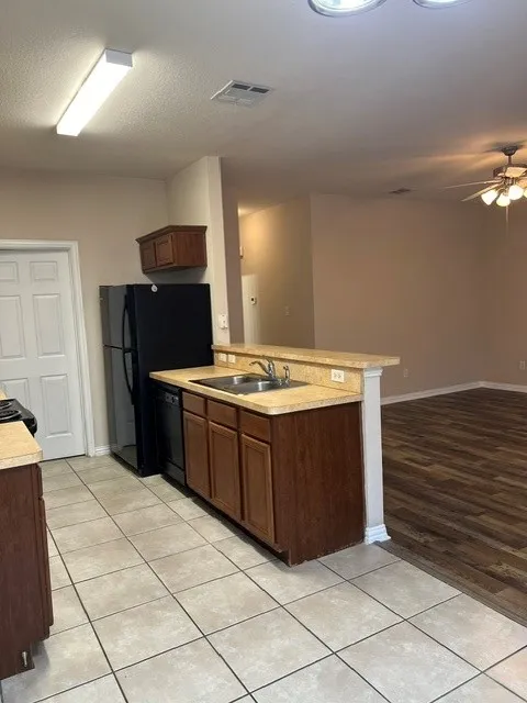 Kitchen featuring a double basin sink, dark wood cabinetry, tile flooring, and a breakfast bar