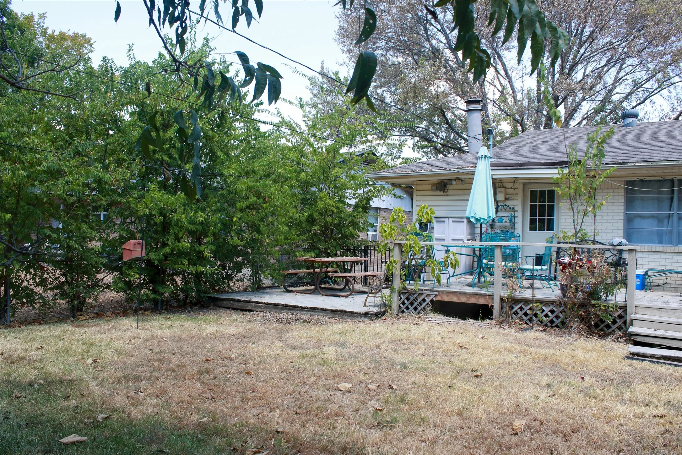 Rear exterior featuring a wood deck, shingle roof, and brick facade
