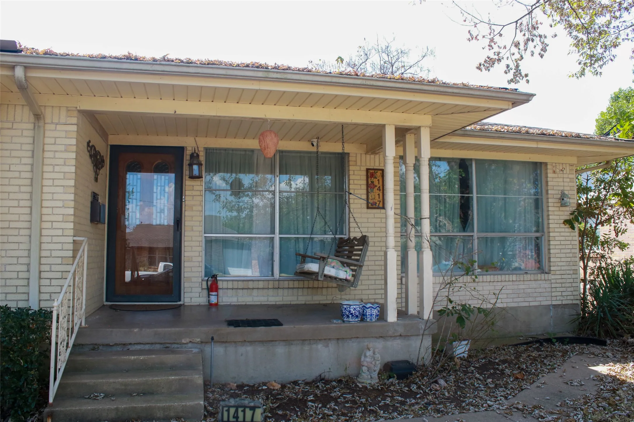 Brick exterior with a covered front porch featuring a full-light storm door and a porch light fixture