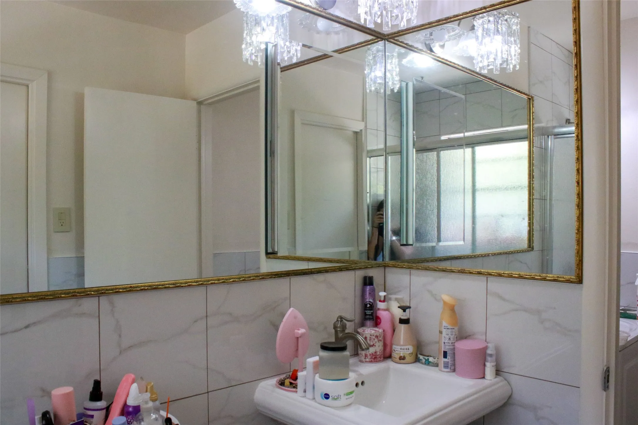 Pedestal sink with a polished chrome faucet, surrounded by tiled walls