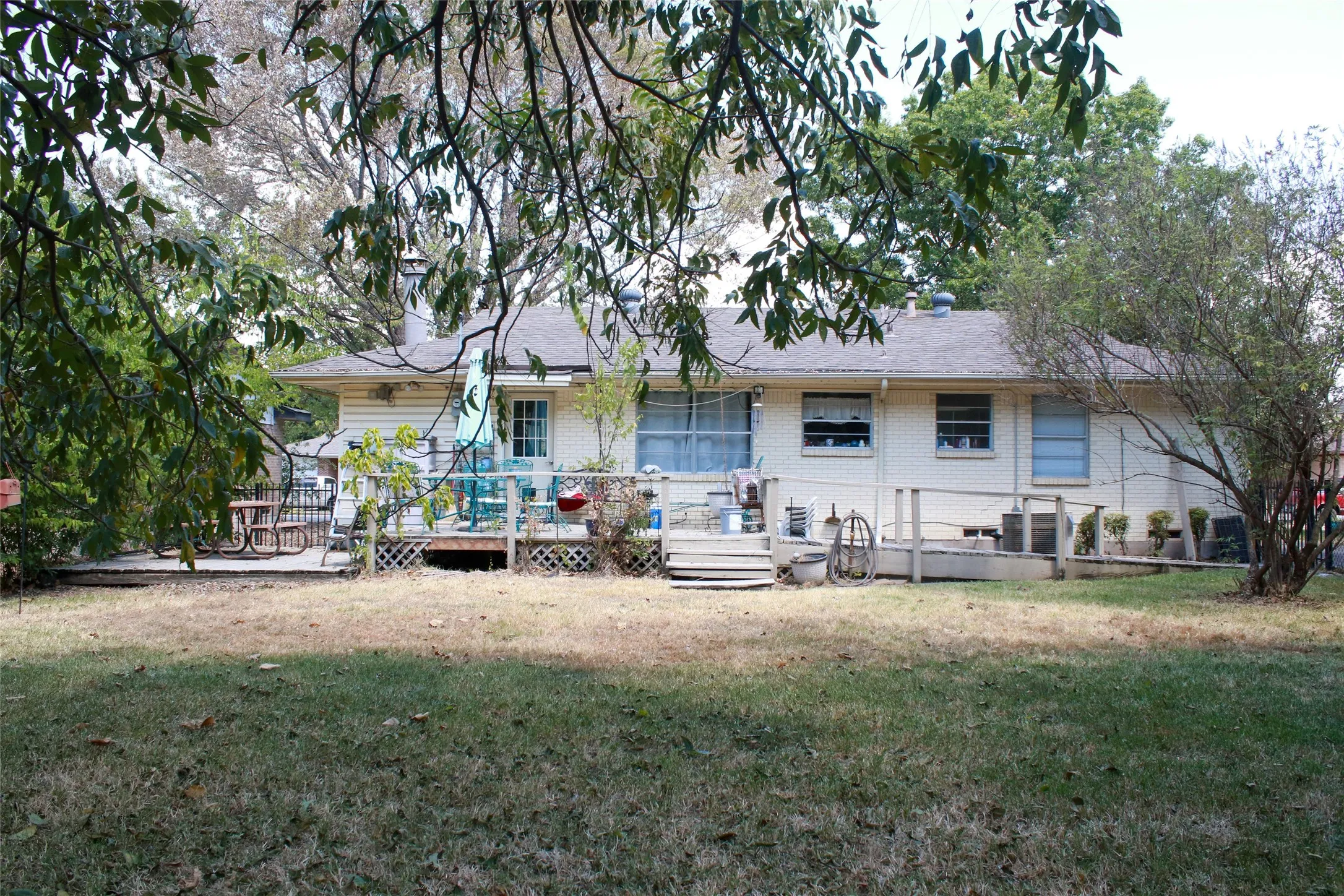 Expansive backyard with a large deck, mature trees, and a ramp for accessibility