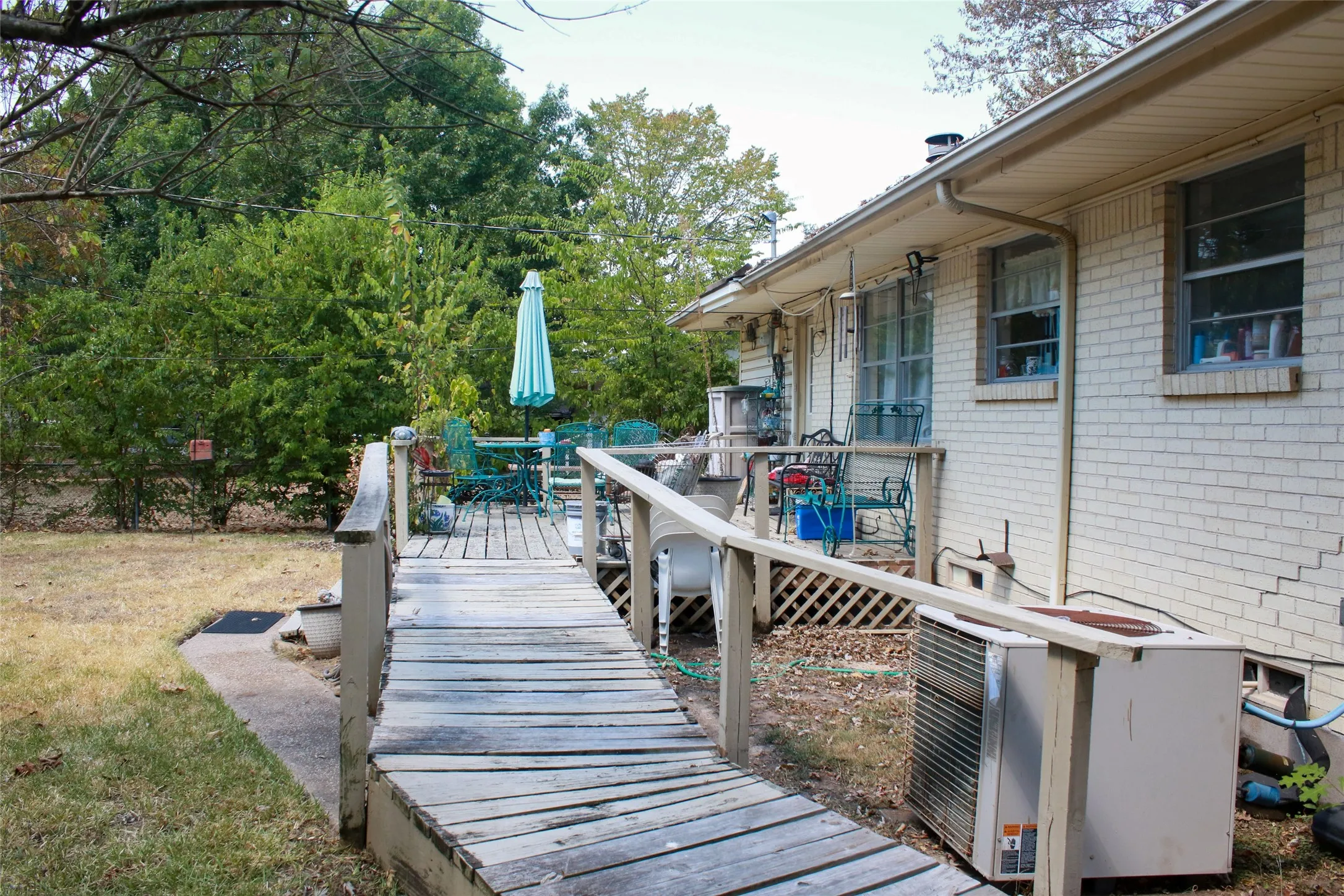 Exterior featuring a wood deck with a ramp, white brick siding, and multiple windows