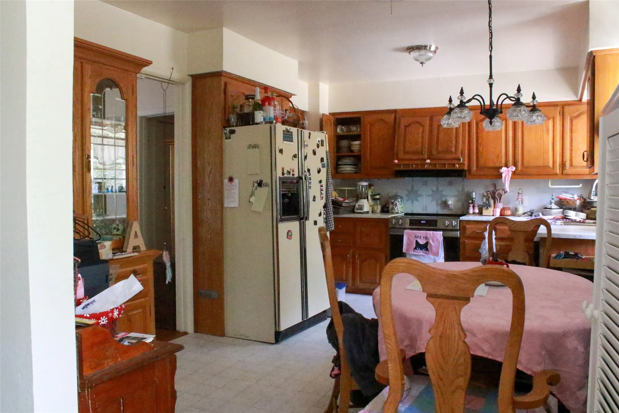 Spacious kitchen featuring wood cabinetry, stainless steel appliances including a side-by-side refrigerator, tile countertops, and a dining area with wood-finish flooring