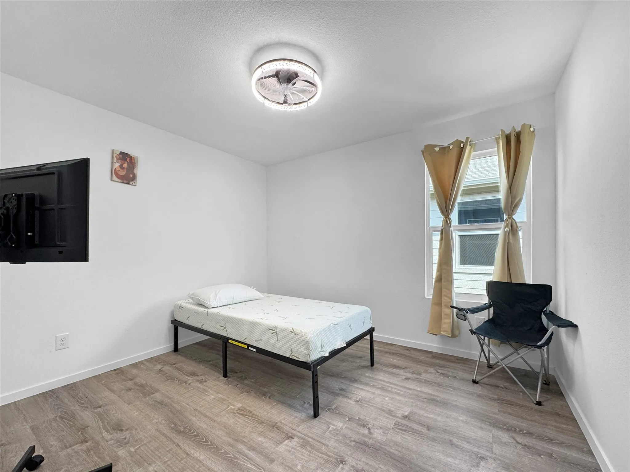 Room with wood-finish flooring, a ceiling-mounted light fixture, and a window