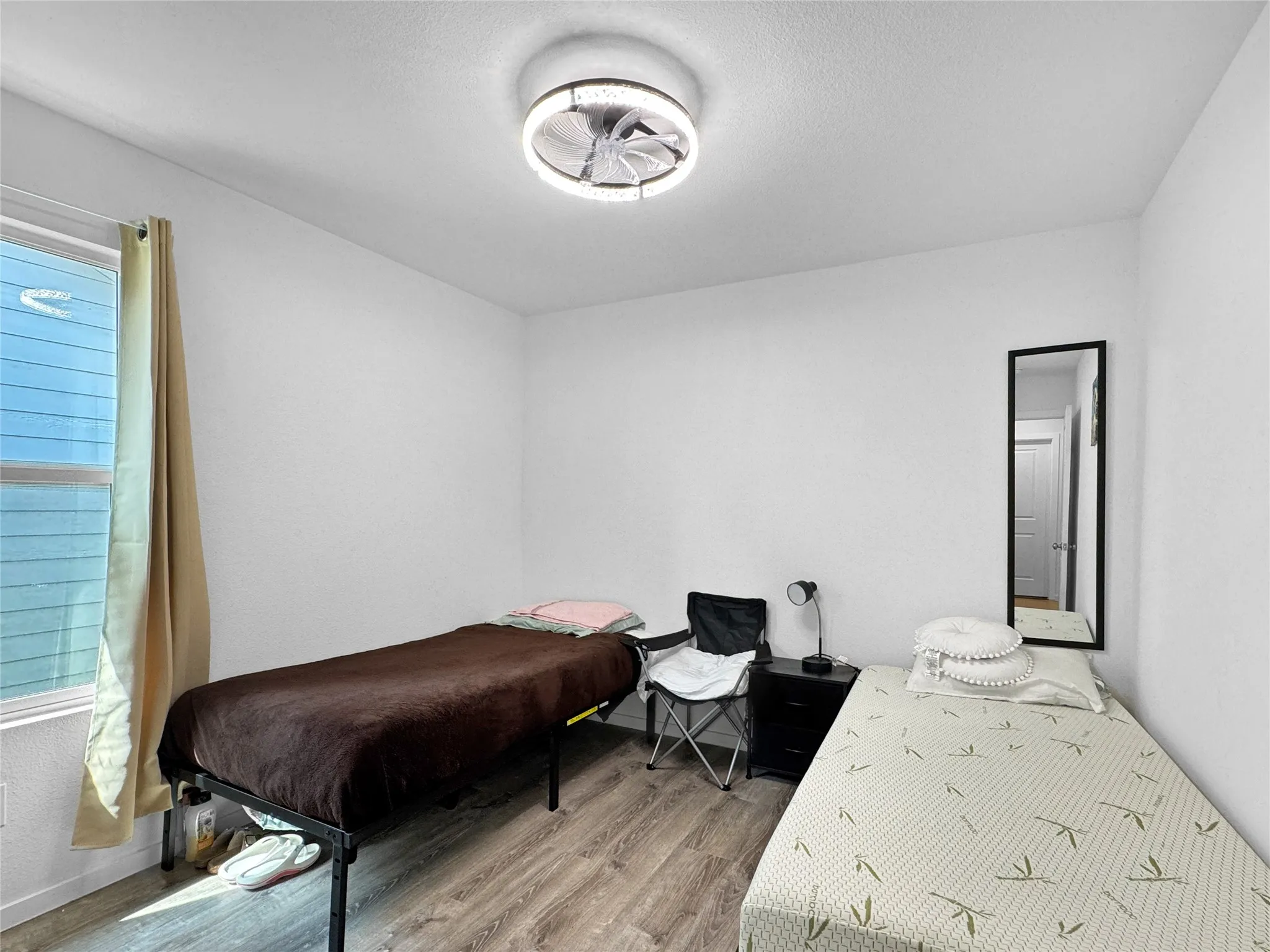White walls, wood-finish flooring, and a contemporary ceiling fan with integrated lighting