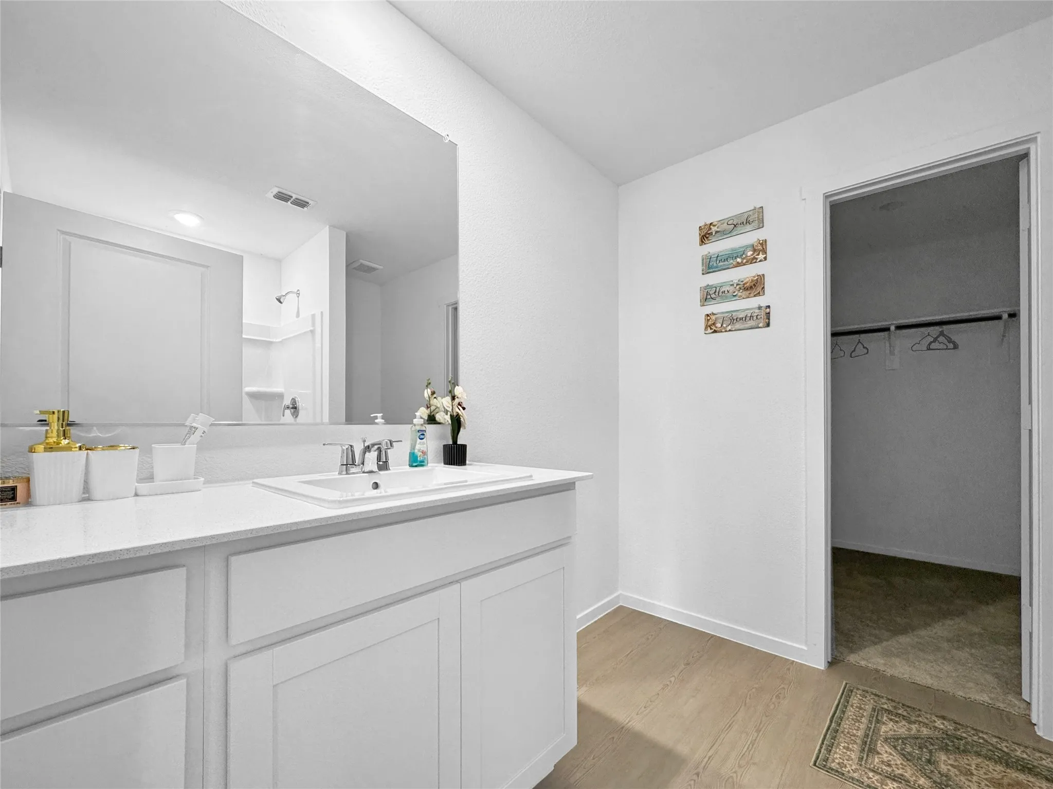 Vanity with an integrated sink, polished chrome faucet, and a large wall-mounted mirror