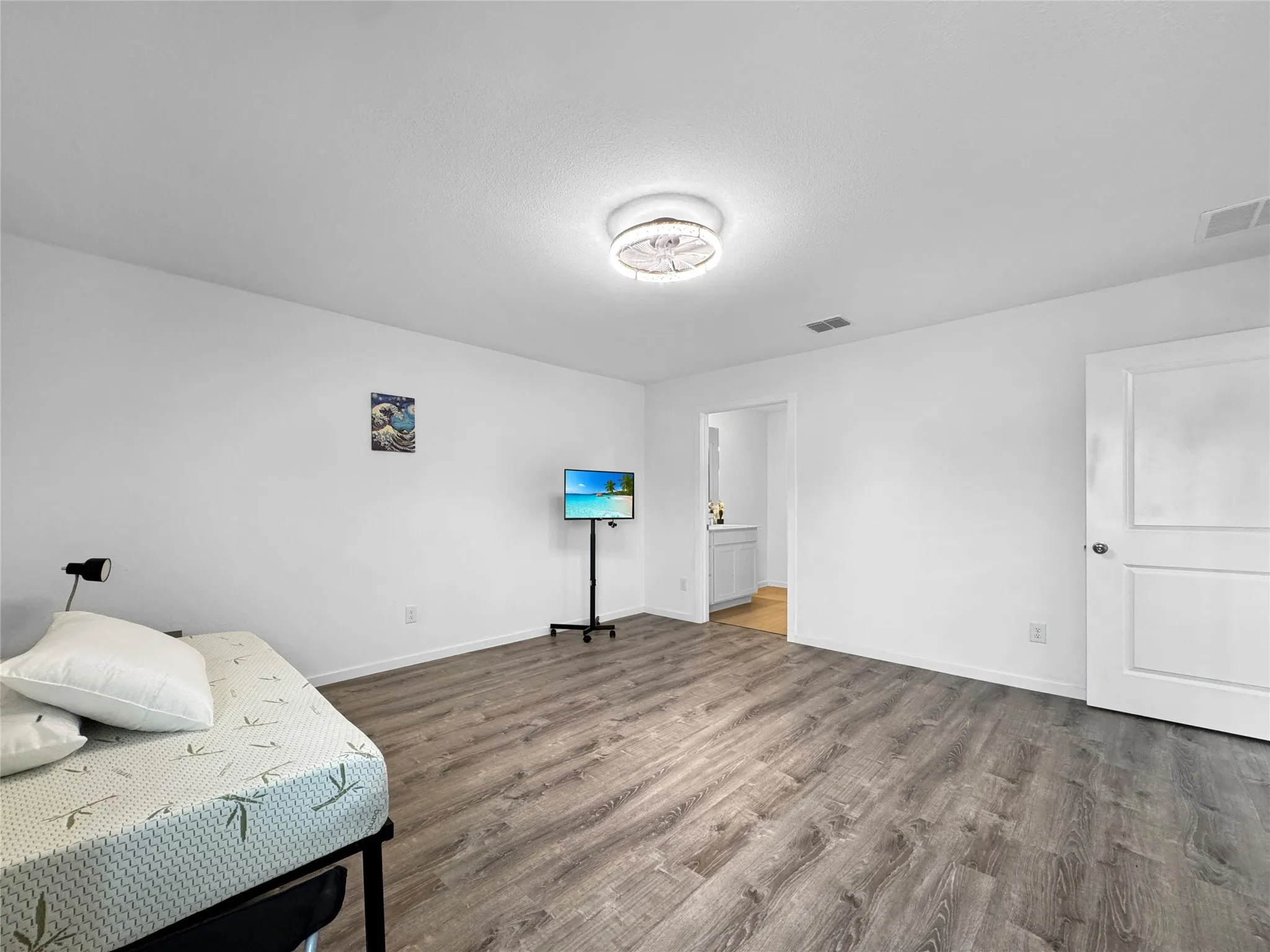 Wood-finish flooring, white walls, white paneled door, and a flush mount ceiling light fixture