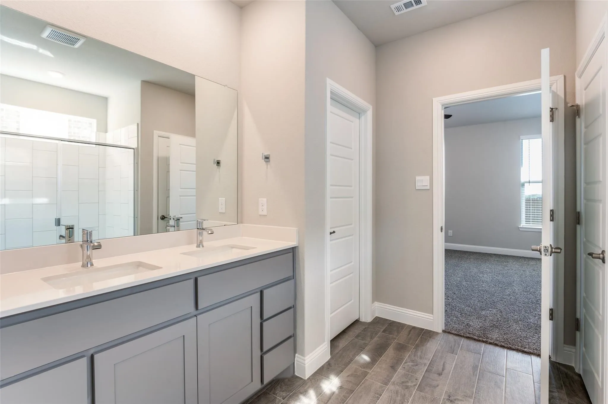 Dual vanity with quartz countertops, chrome fixtures, and a large wall-mounted mirror