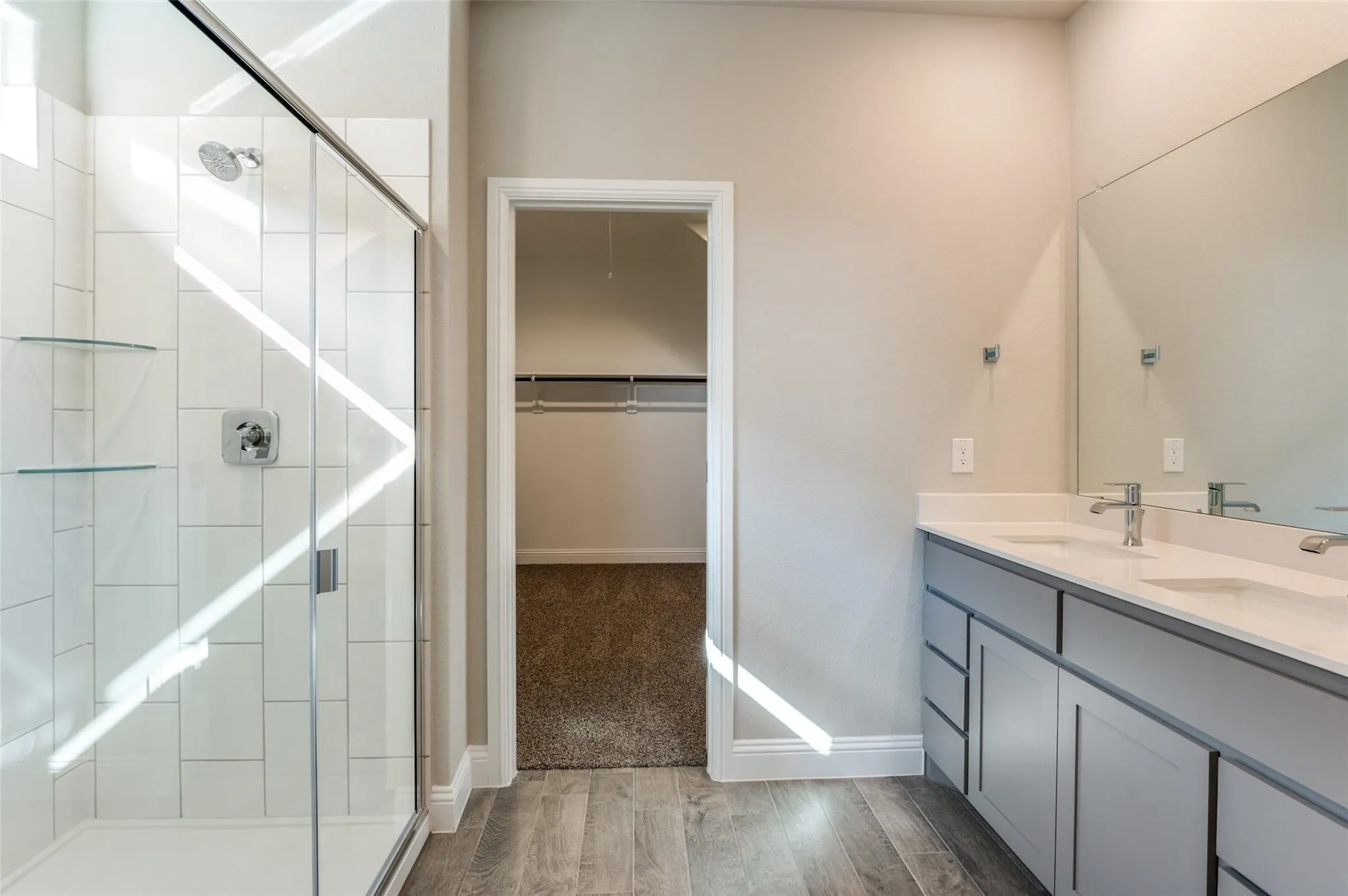 Walk-in shower with clear glass enclosure and white tile surround