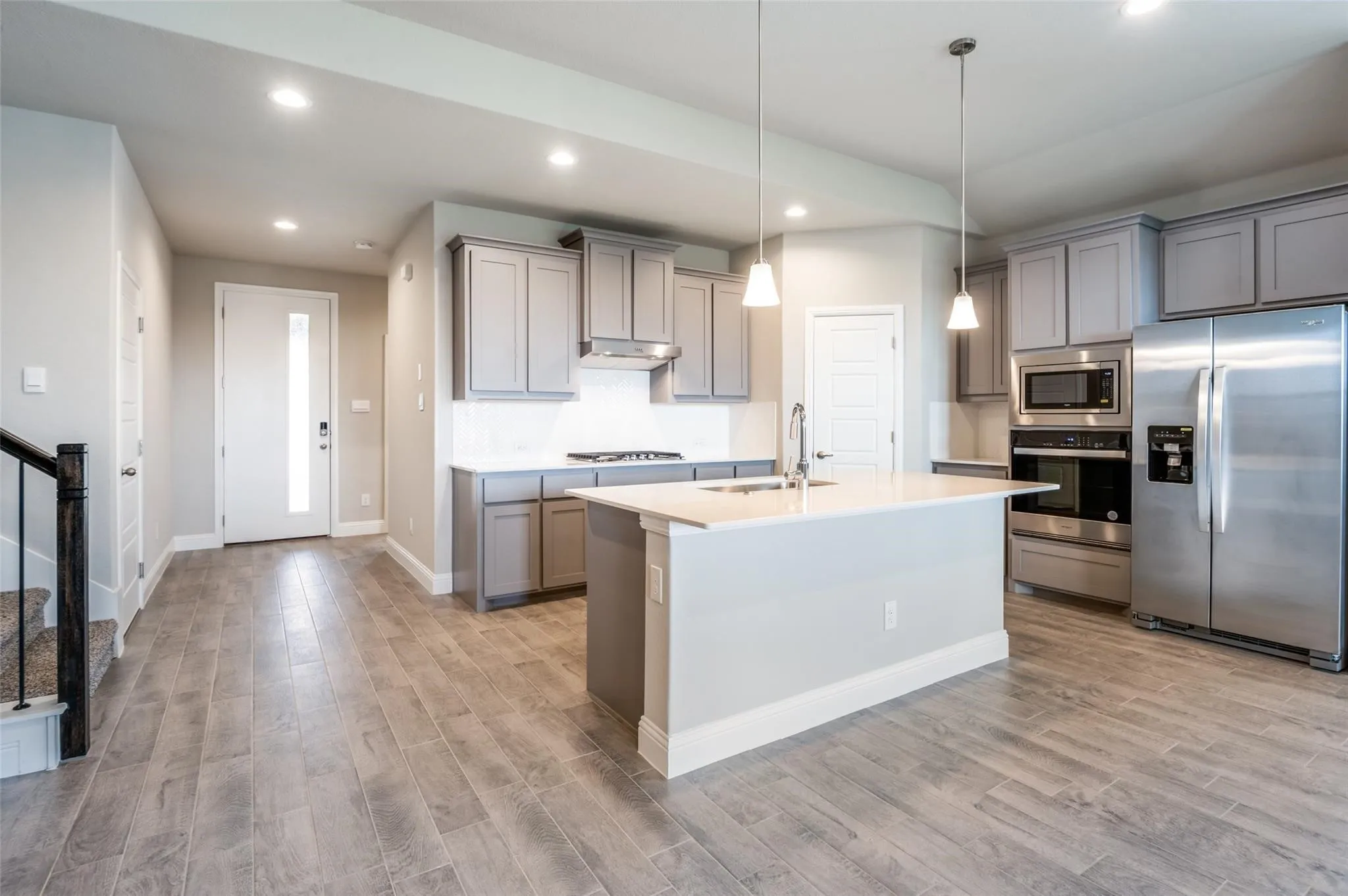 Open-concept kitchen with a central island, stainless steel appliances, and grey cabinetry
