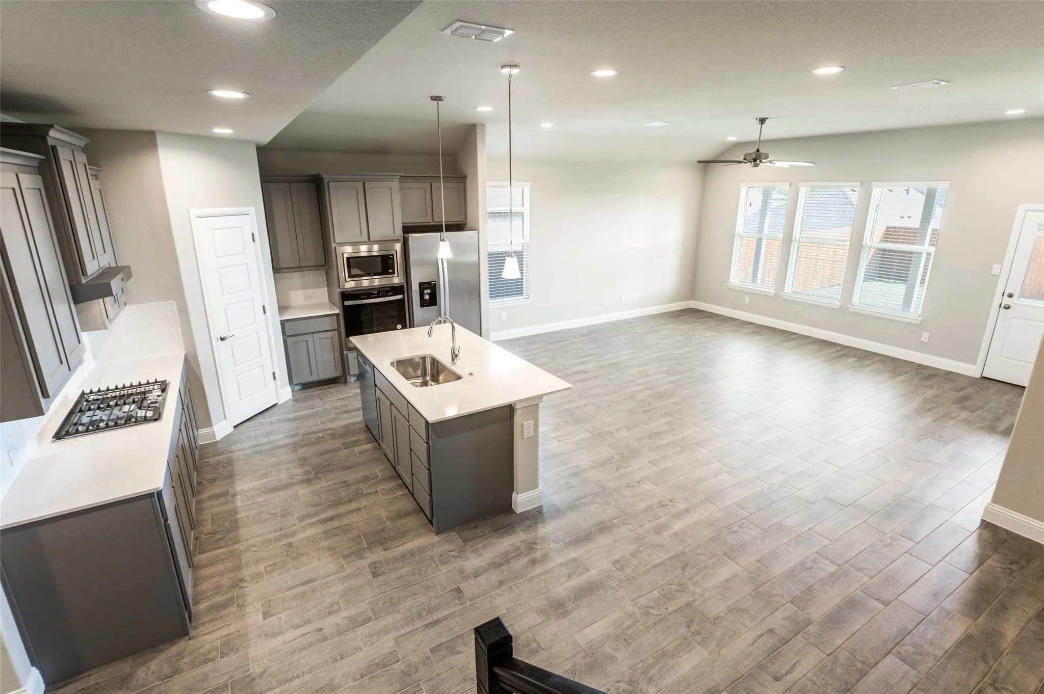 Open-concept living area with wood-finish flooring, recessed lighting, and a ceiling fan