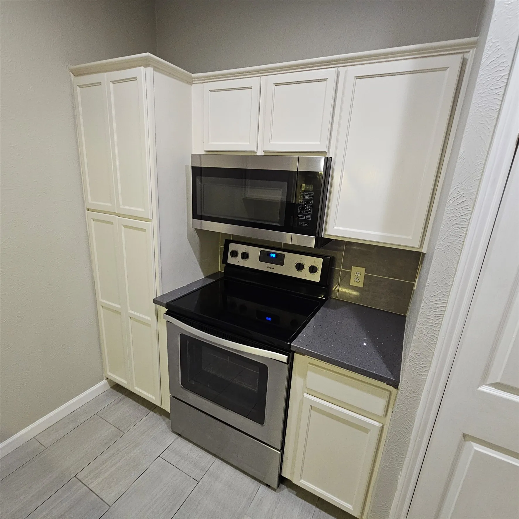 Kitchen with stainless steel appliances, tasteful backsplash, dark stone counters, and wood finish floors