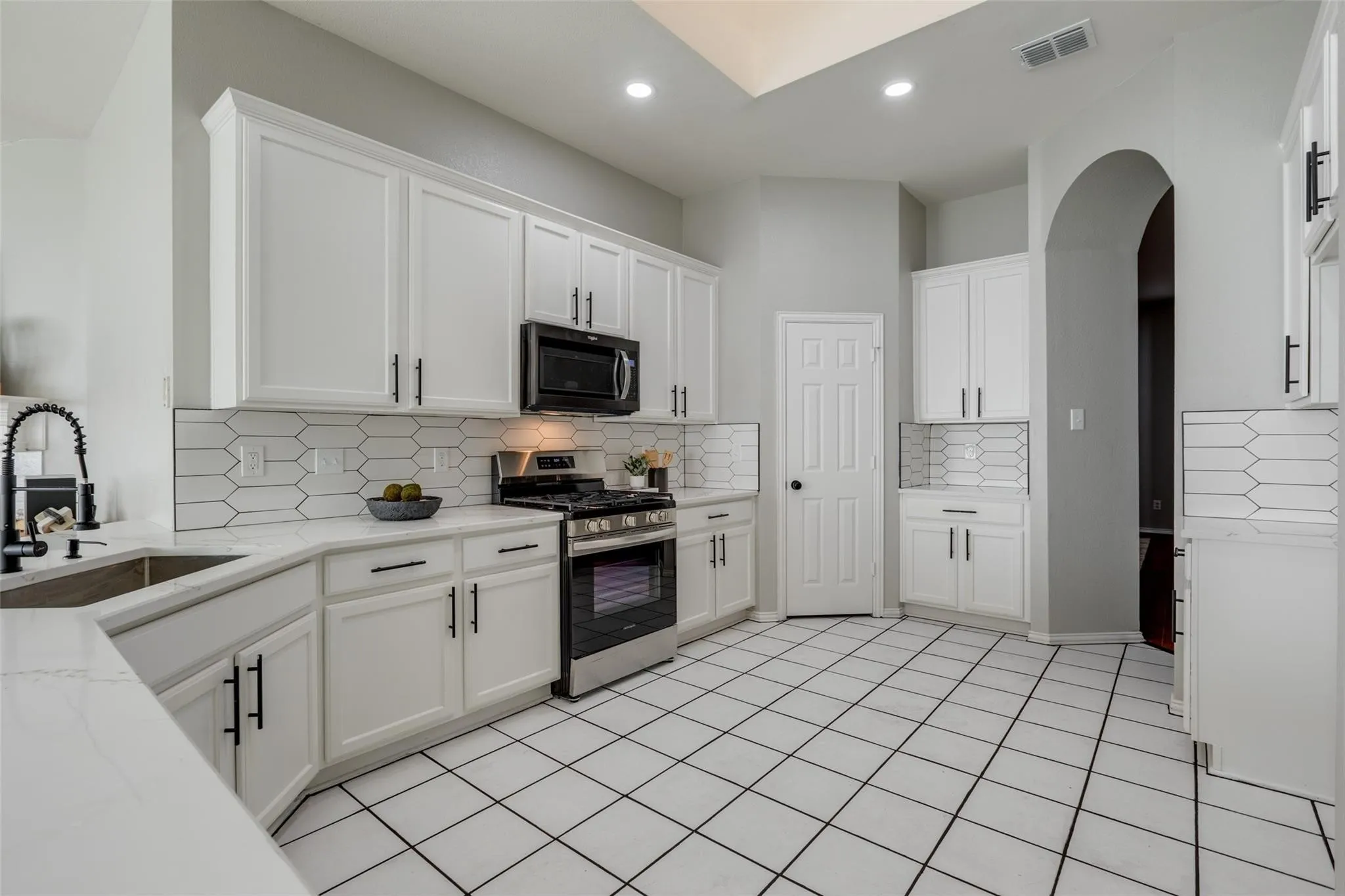 Kitchen featuring white cabinetry, light-toned countertops, a stainless steel range, and a patterned tile backsplash