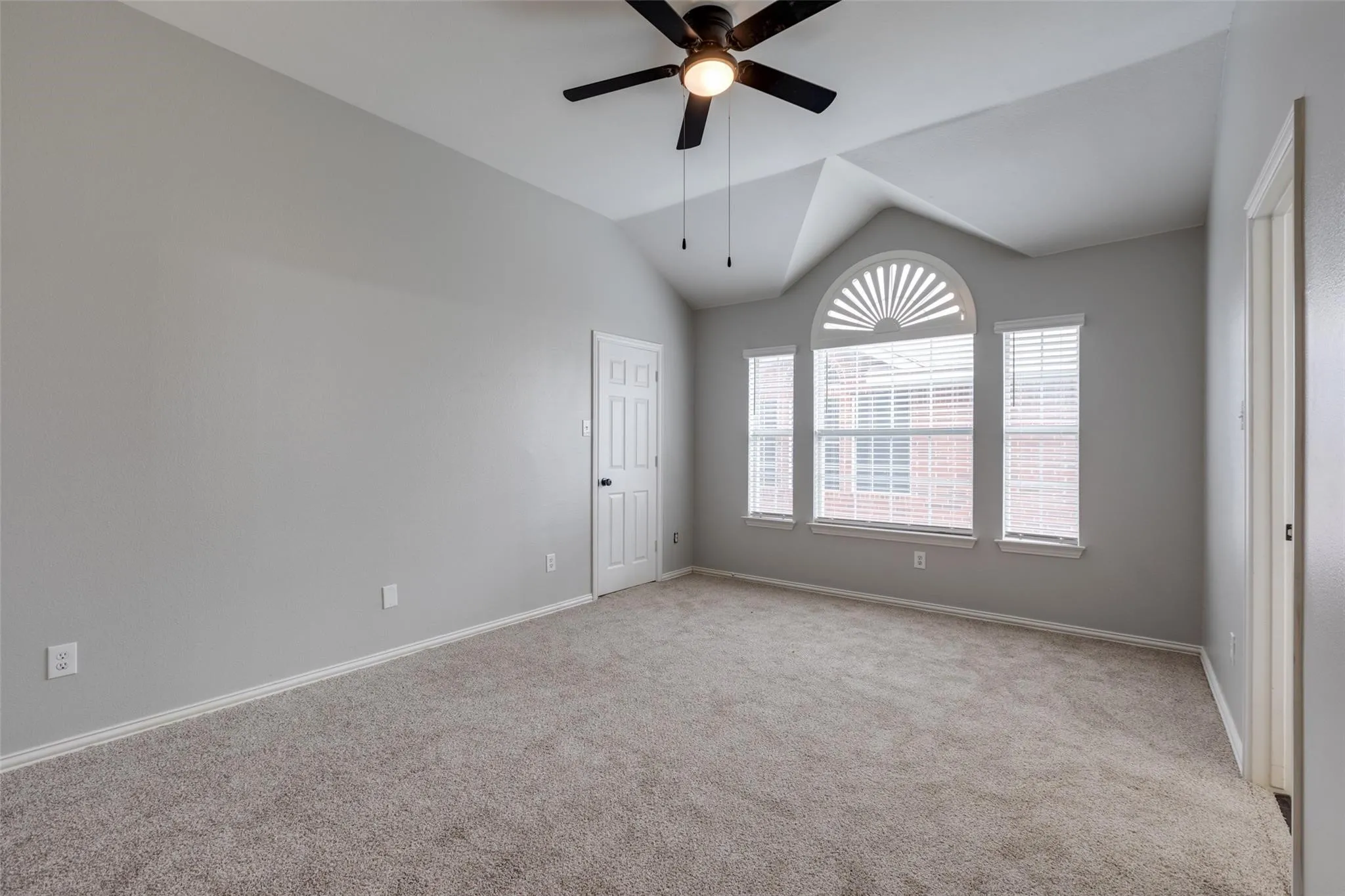 Vaulted ceiling room featuring light gray walls and plush carpeting