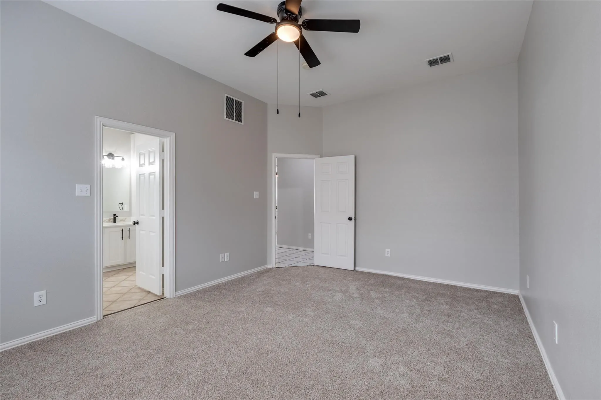 Spacious room featuring vaulted ceilings, a ceiling fan with integrated lighting, and neutral-toned carpet flooring