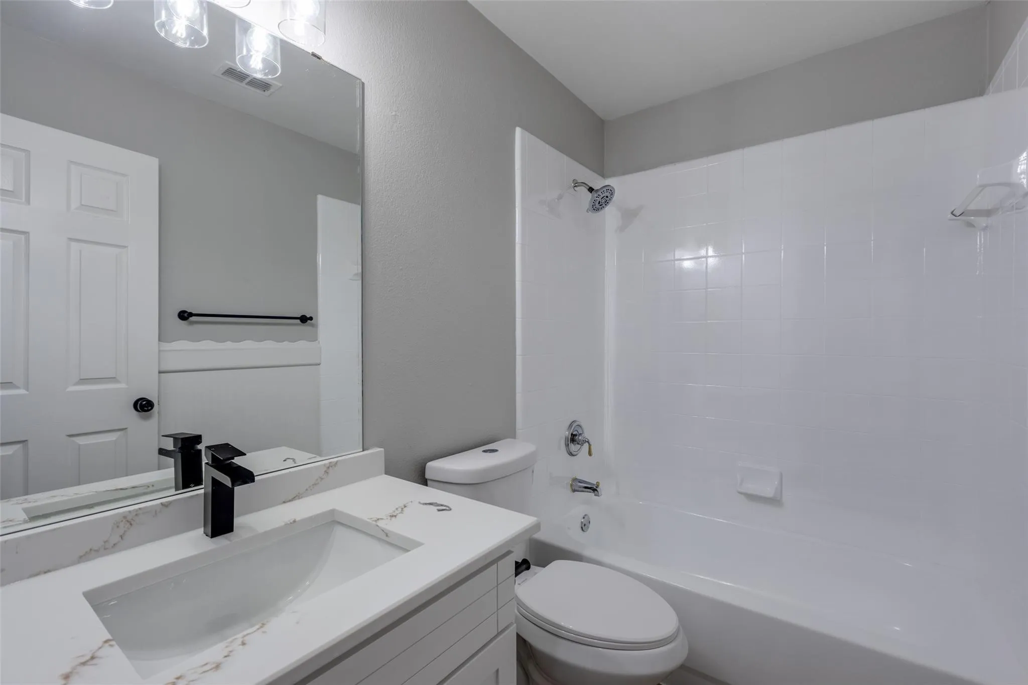 Bathroom featuring a white vanity with a rectangular undermount sink, a quartz-finish countertop, and a matte black faucet