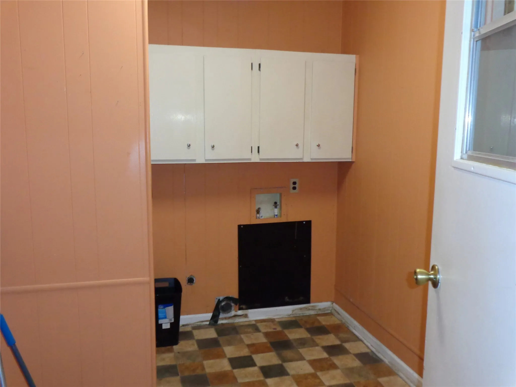 Utility area featuring upper cabinetry, a checkerboard floor, and a window