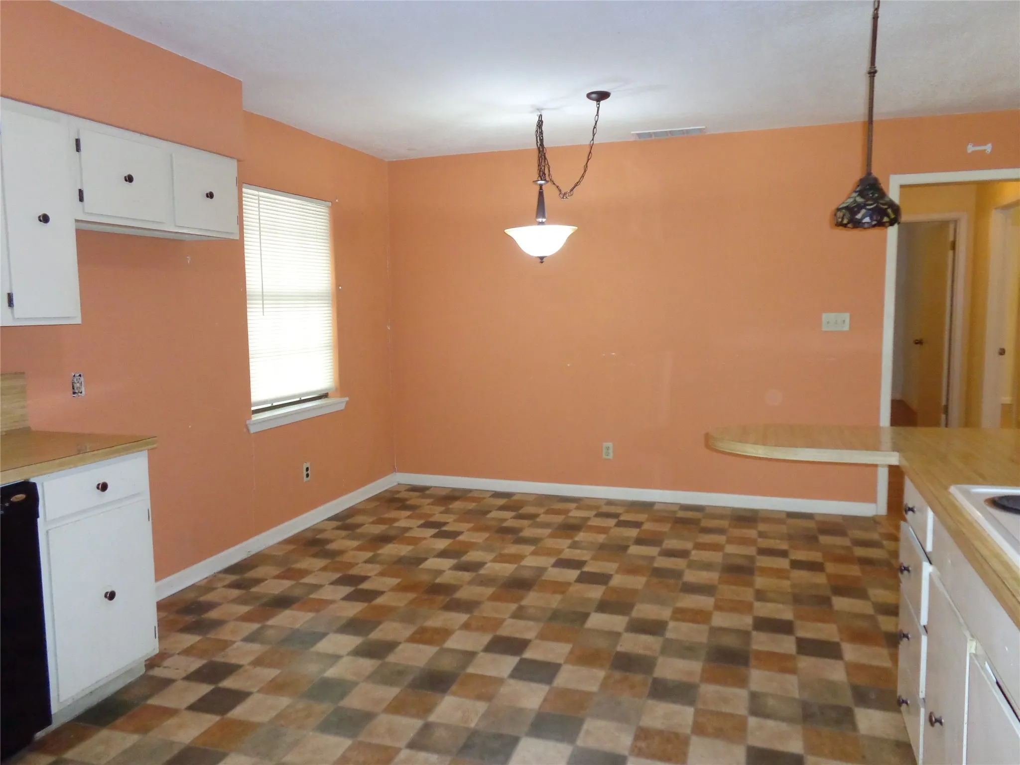 Galley kitchen with white cabinetry, checkerboard tile flooring, and a built-in breakfast bar