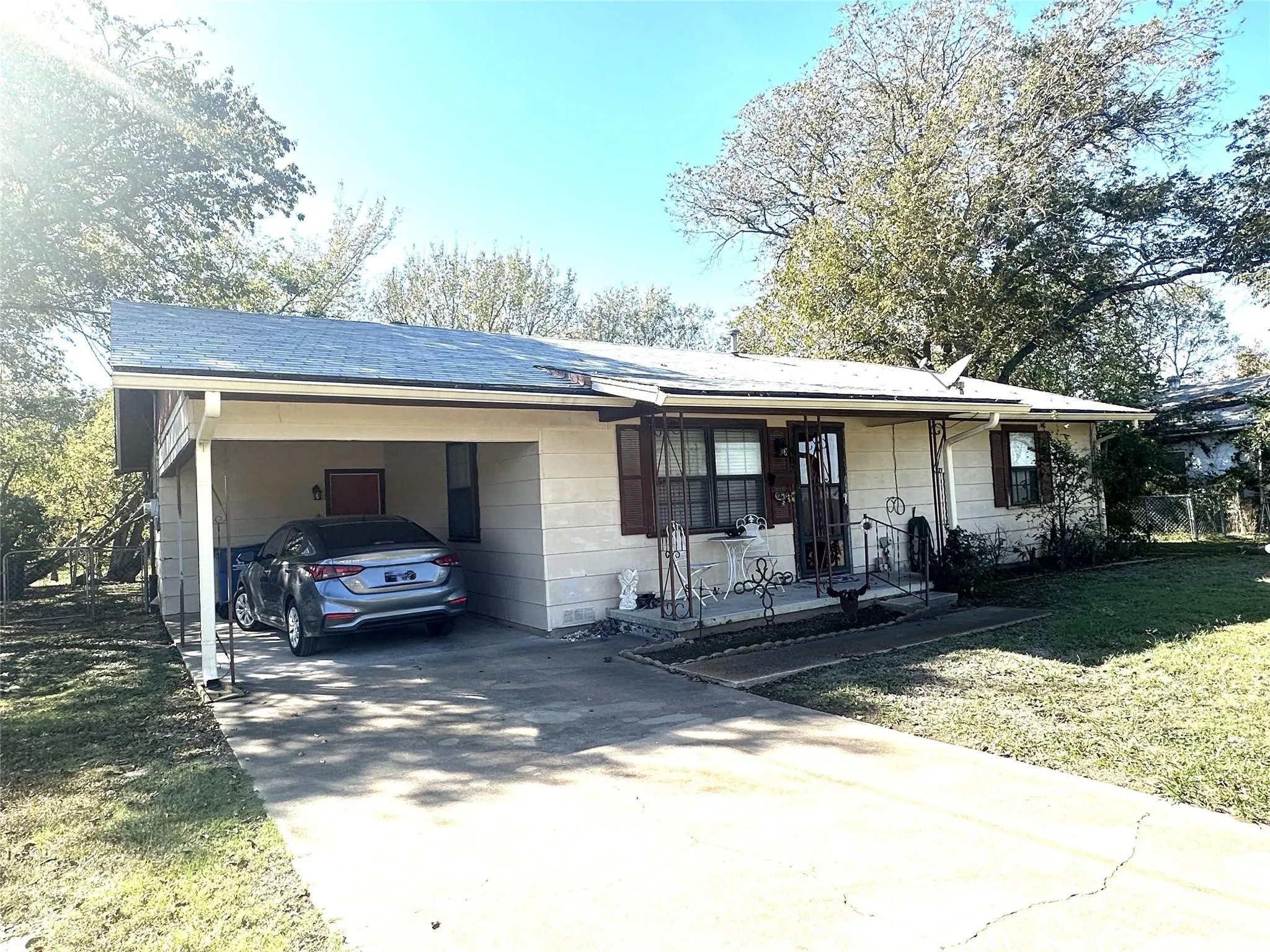 Single-story residence featuring a carport, concrete driveway, and front porch with wrought iron railing
